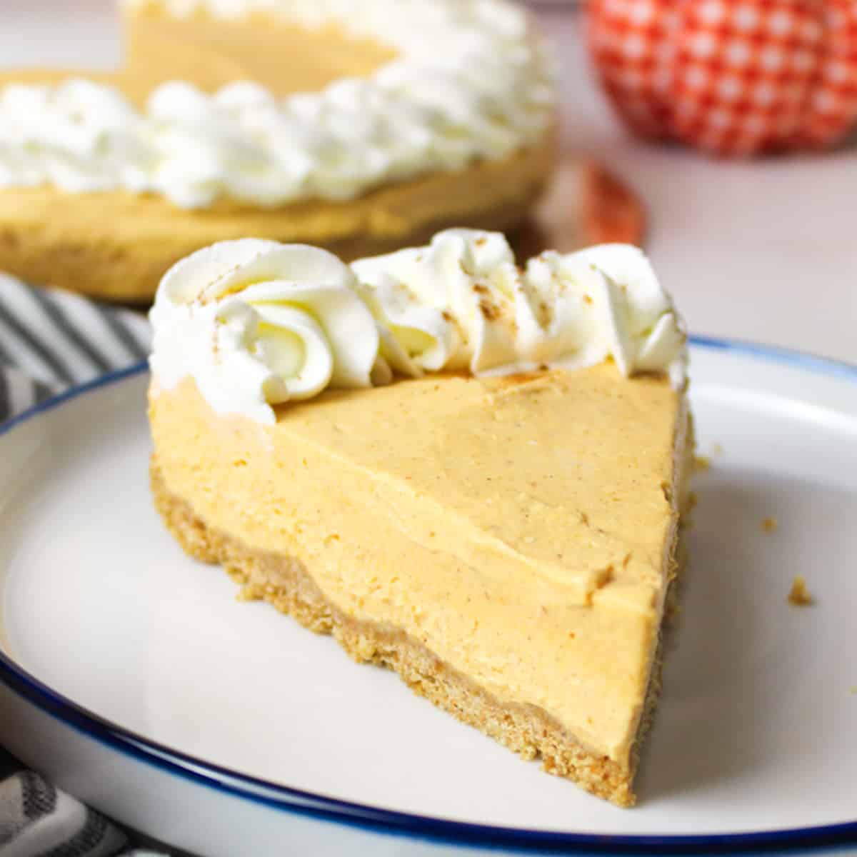 a slice of no bake pumpkin cheesecake with more cheesecake in the background.
