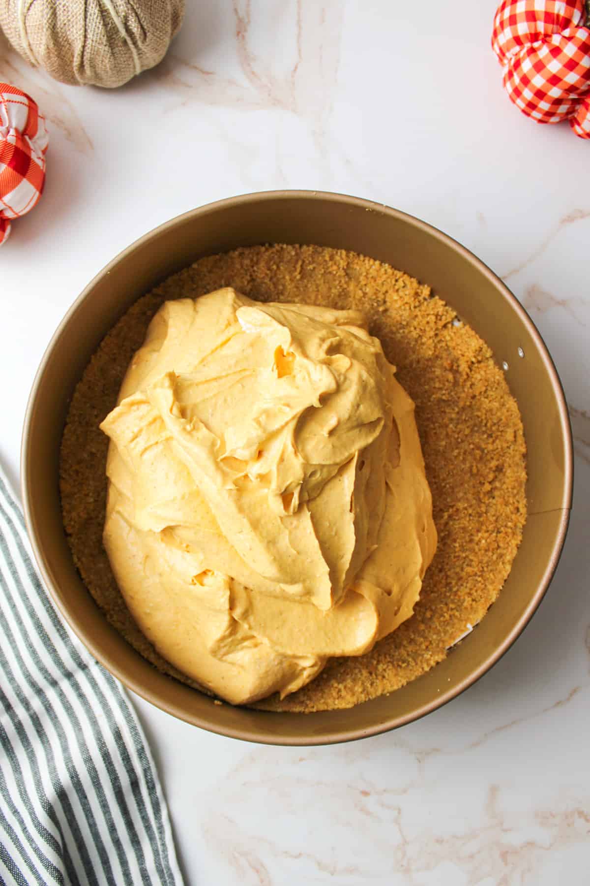 no bake pumpkin cheesecake filling piled on top of a pressed graham cracker crust