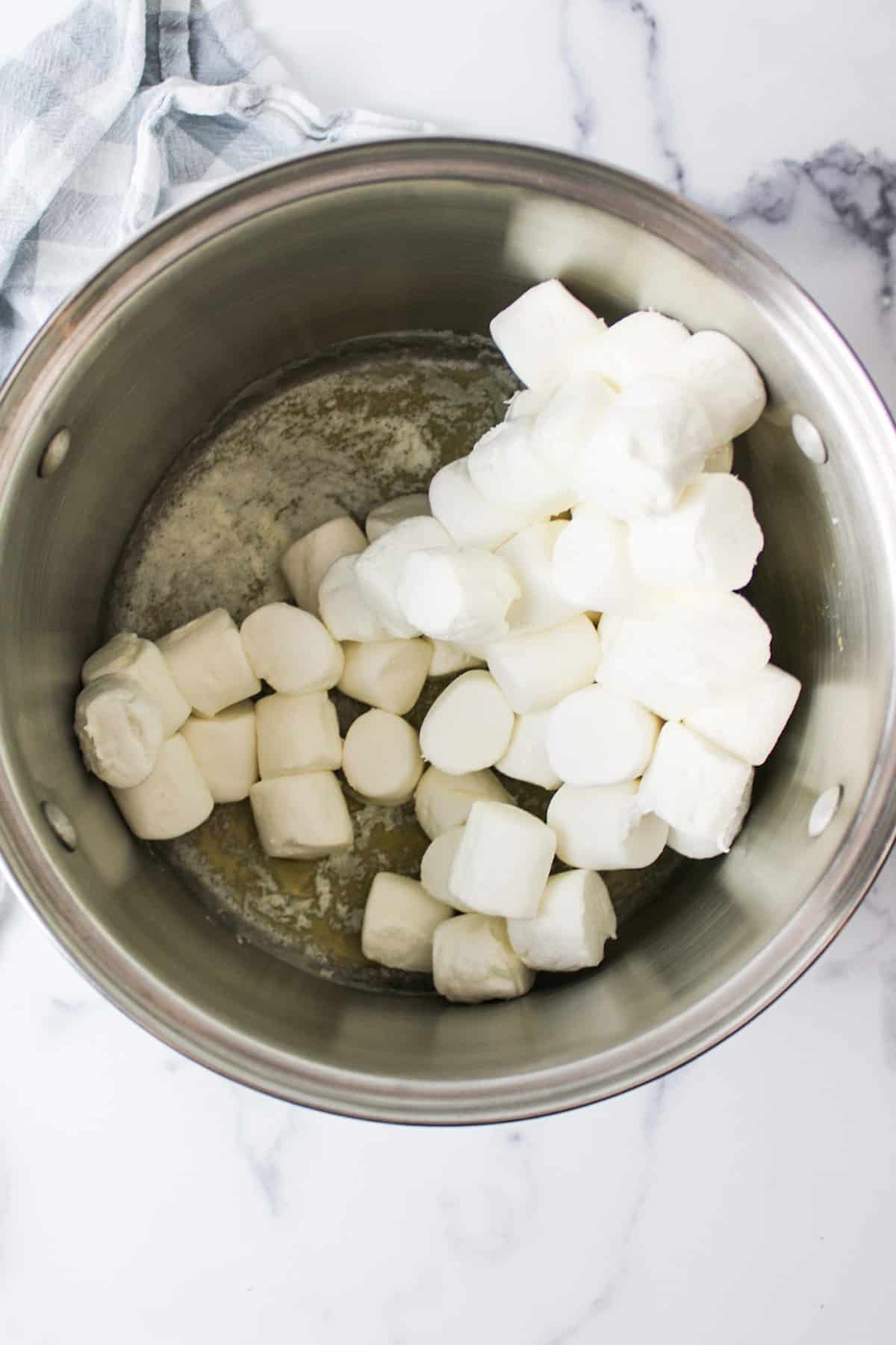 large marshmallows added to a large pot of melted butter.