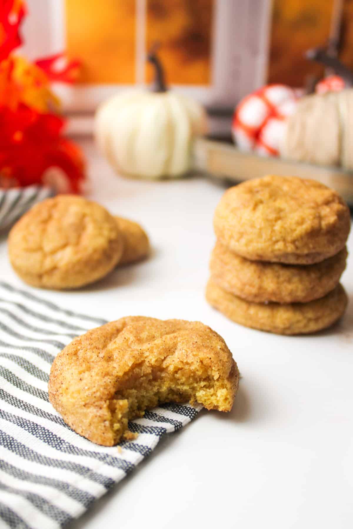 stacked pumpkin spice snickerdoodle cookies, one with a missing bite in front.