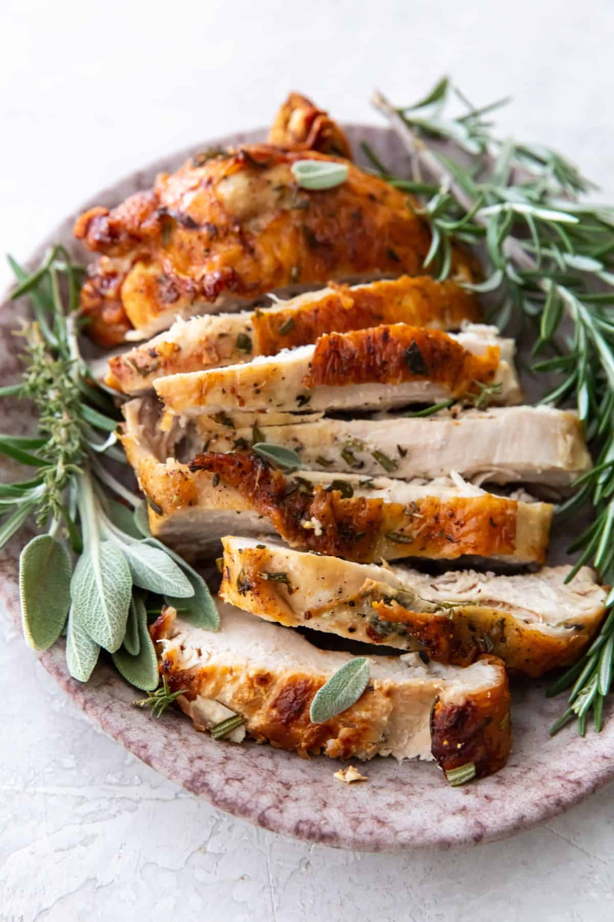 air fried turkey breast on a plate with fresh green herbs.