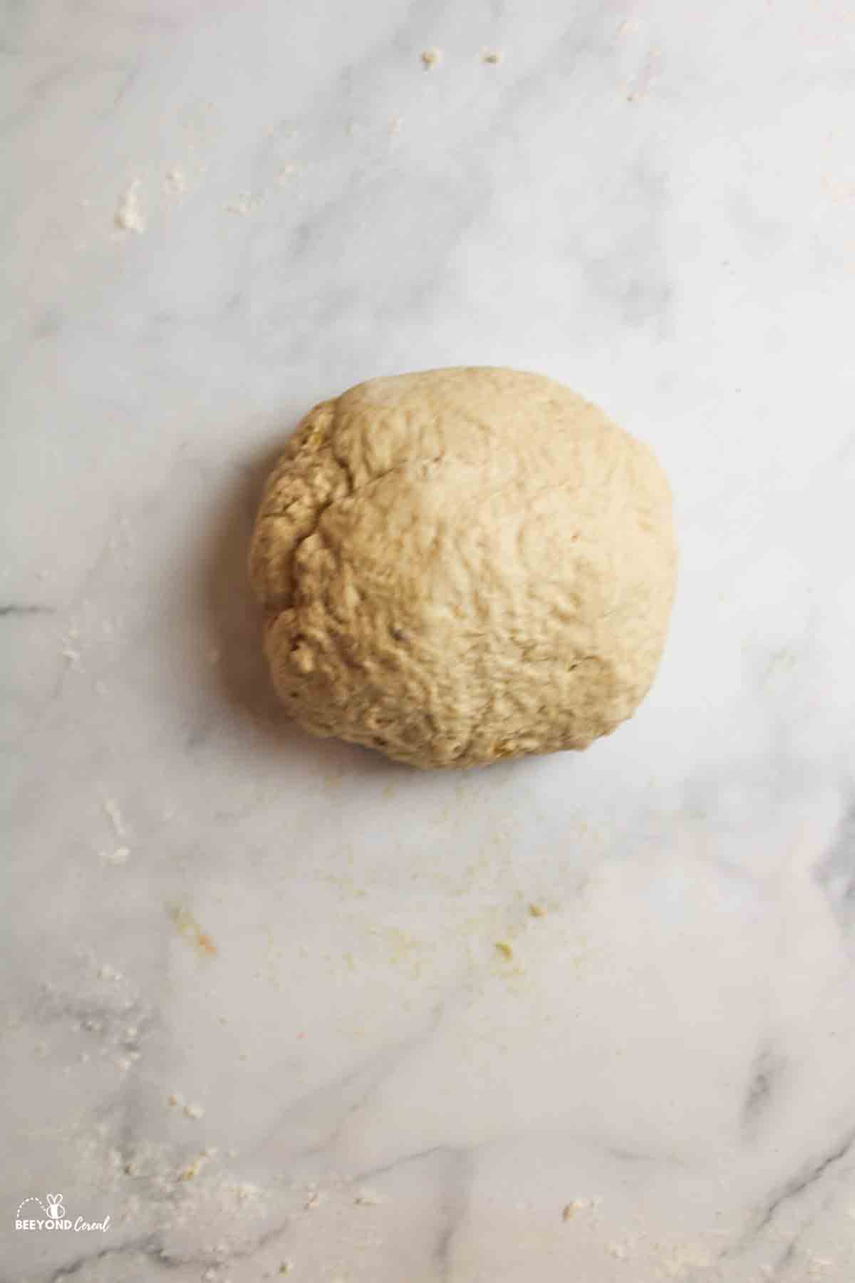 elastic ball of banana bagel dough on a counter.
