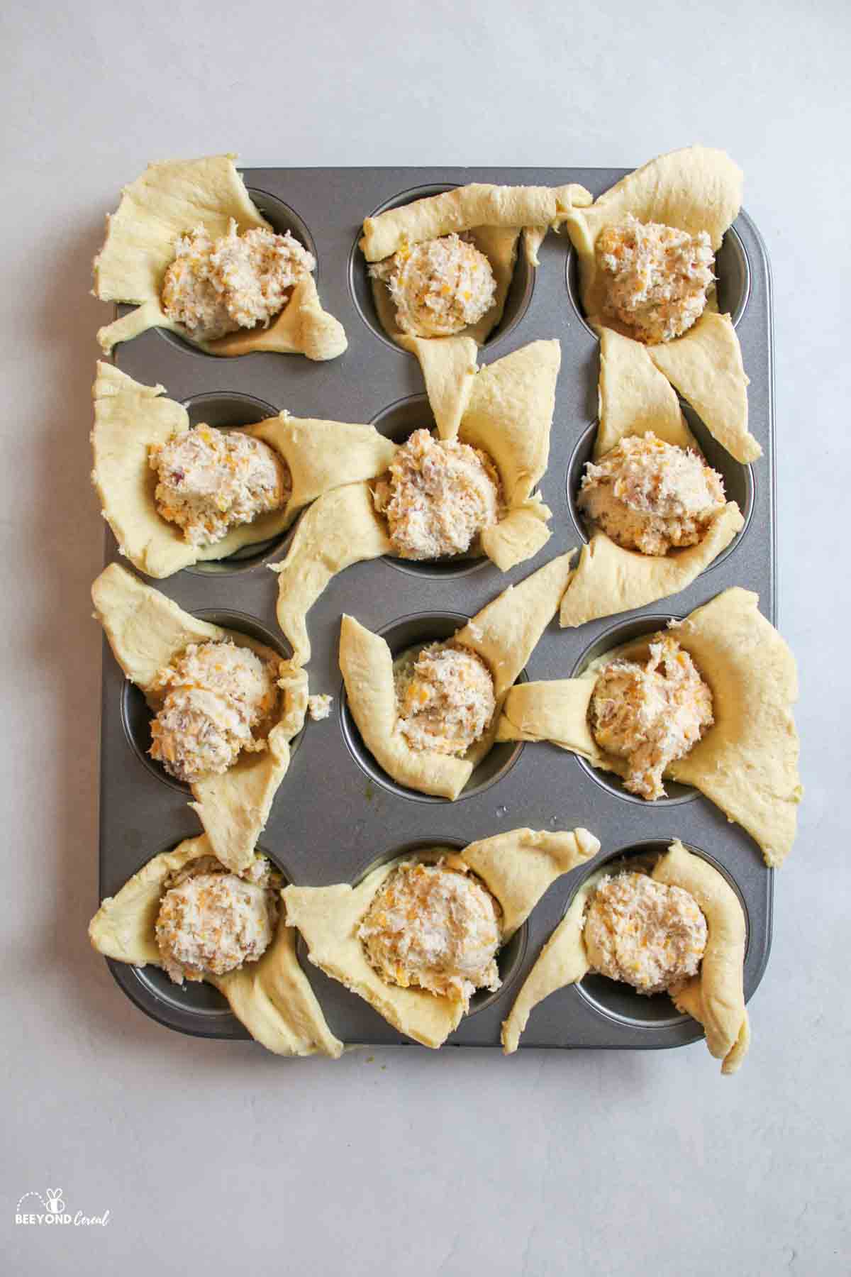 filling in triangles of crescent dough in a muffin pan