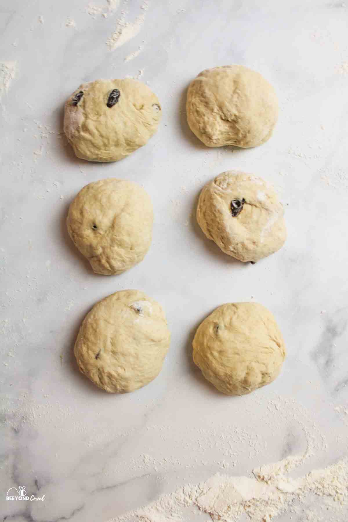 cinnamon raisin bagel dough divided into 6 sections and on a floured surface.