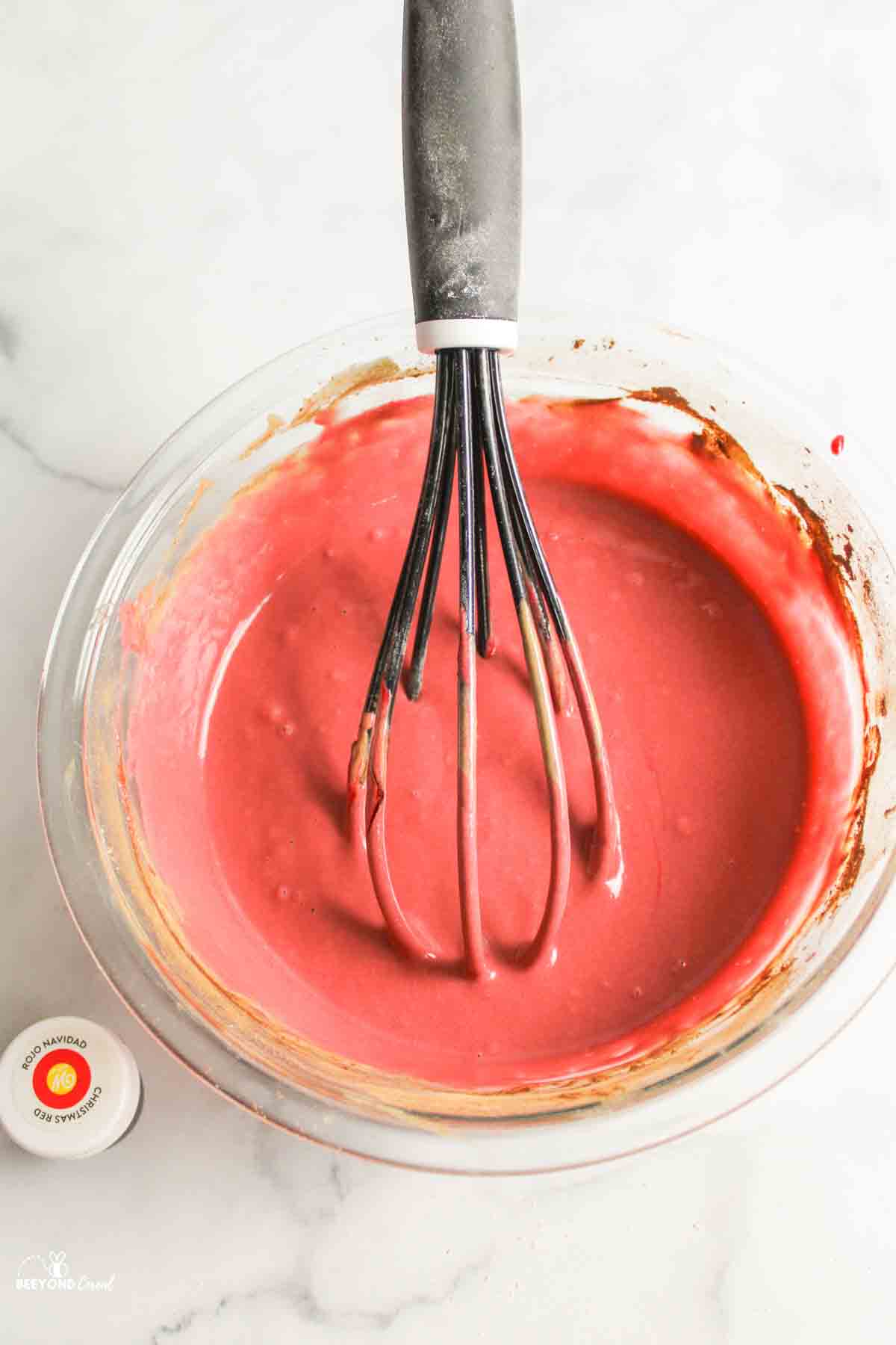 red colored batter in a bowl with a whisk.
