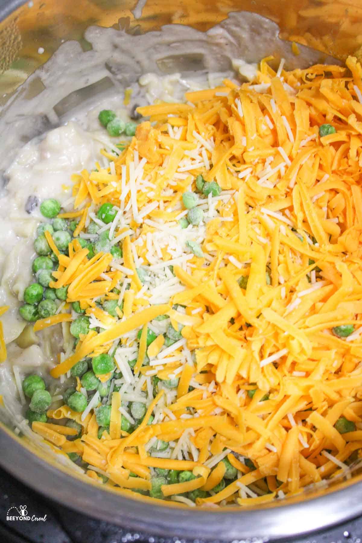 frozen peas and shredded cheese added to instant pot of tuna noodle casserole