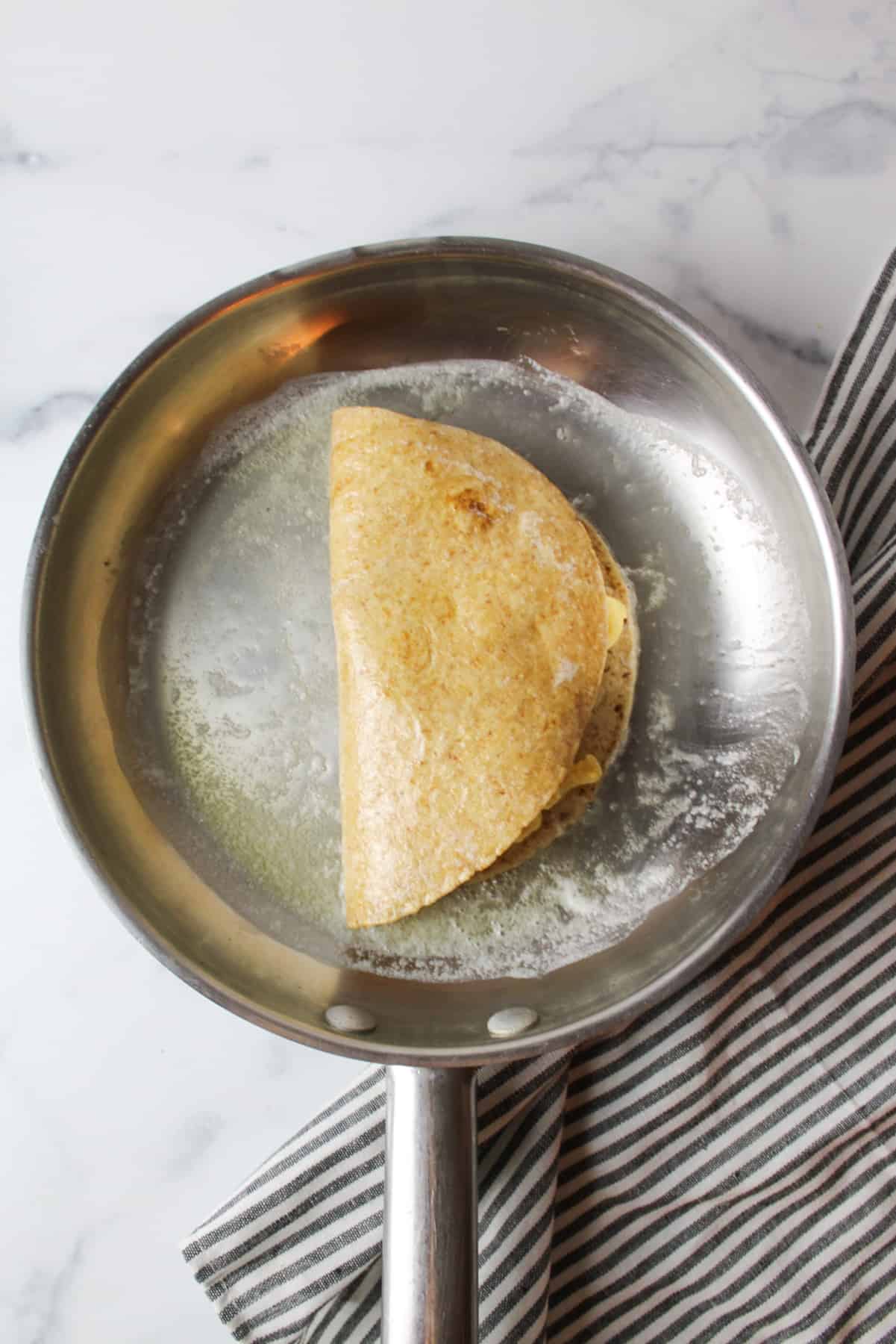 folded and filled quesadilla in a melted butter covered skillet