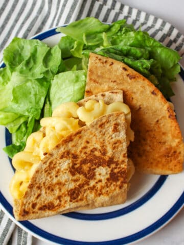 two halved of mac and cheese stuffed quesadilla with salad.