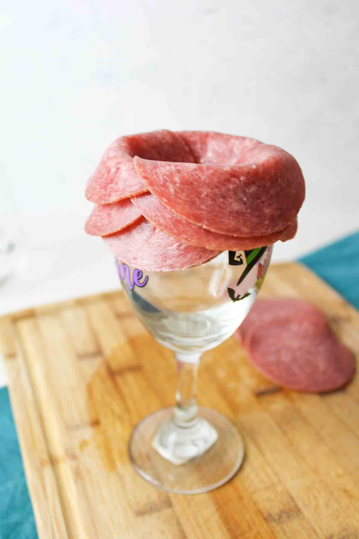 several rows of round deli meat folded over a wine glass rim