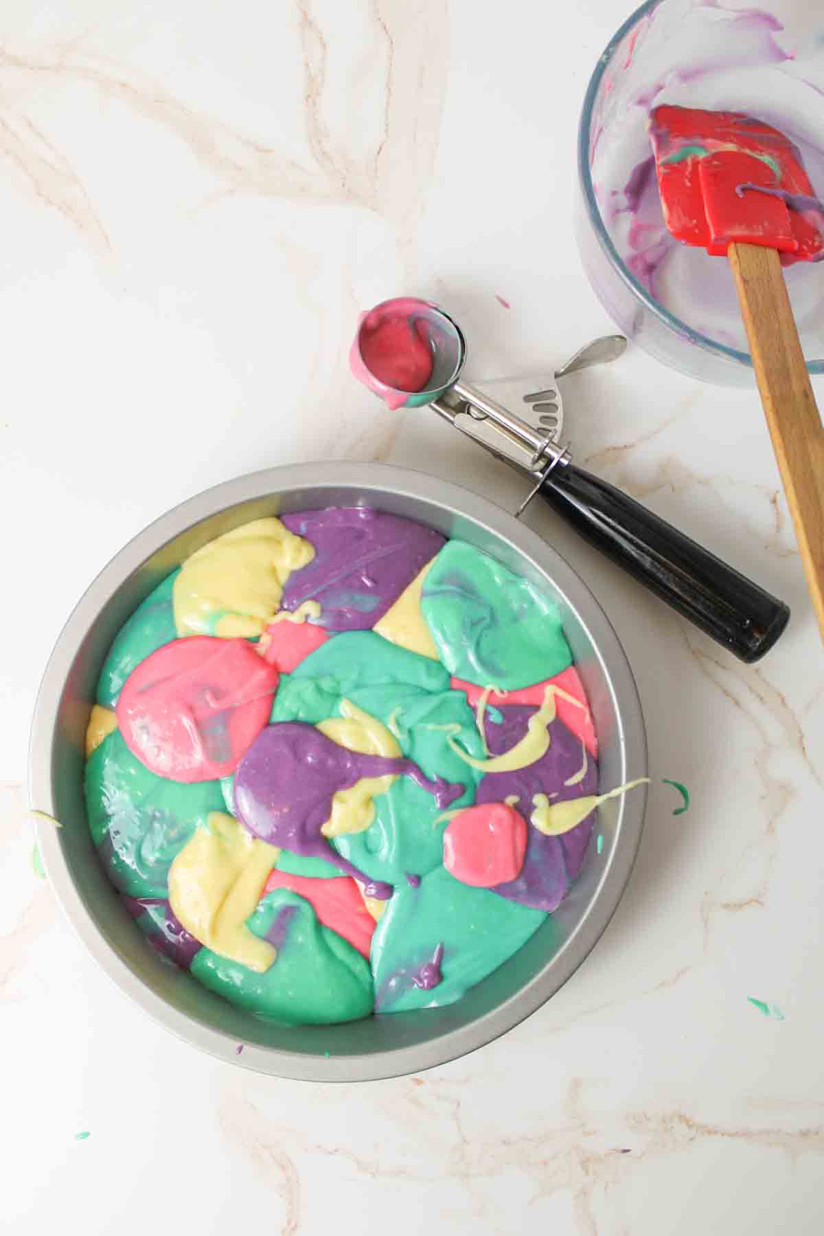 a filled cake pan of colorful splashes of pastel cake batter