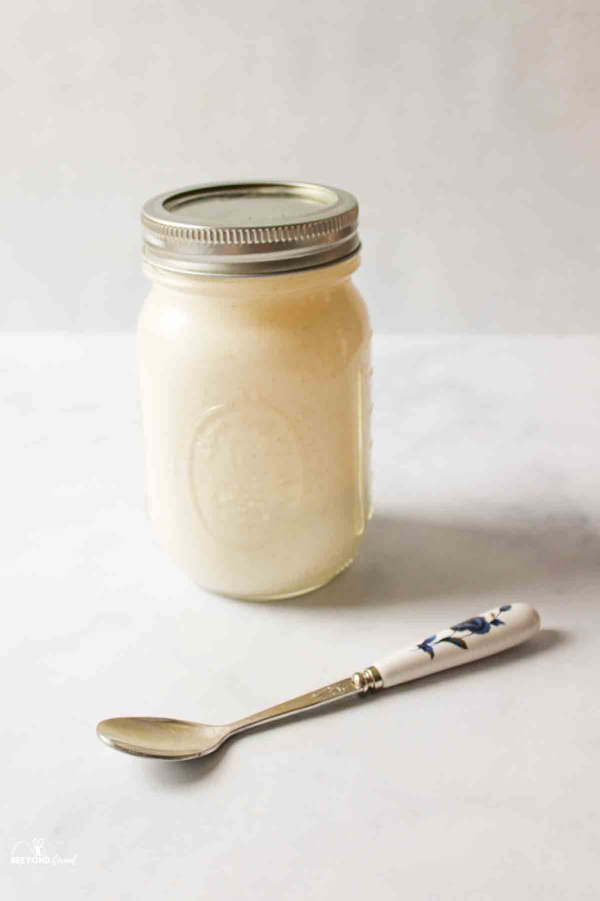 Peanut butter ice cream ingredients in sealed Mason jar, spoon in front.