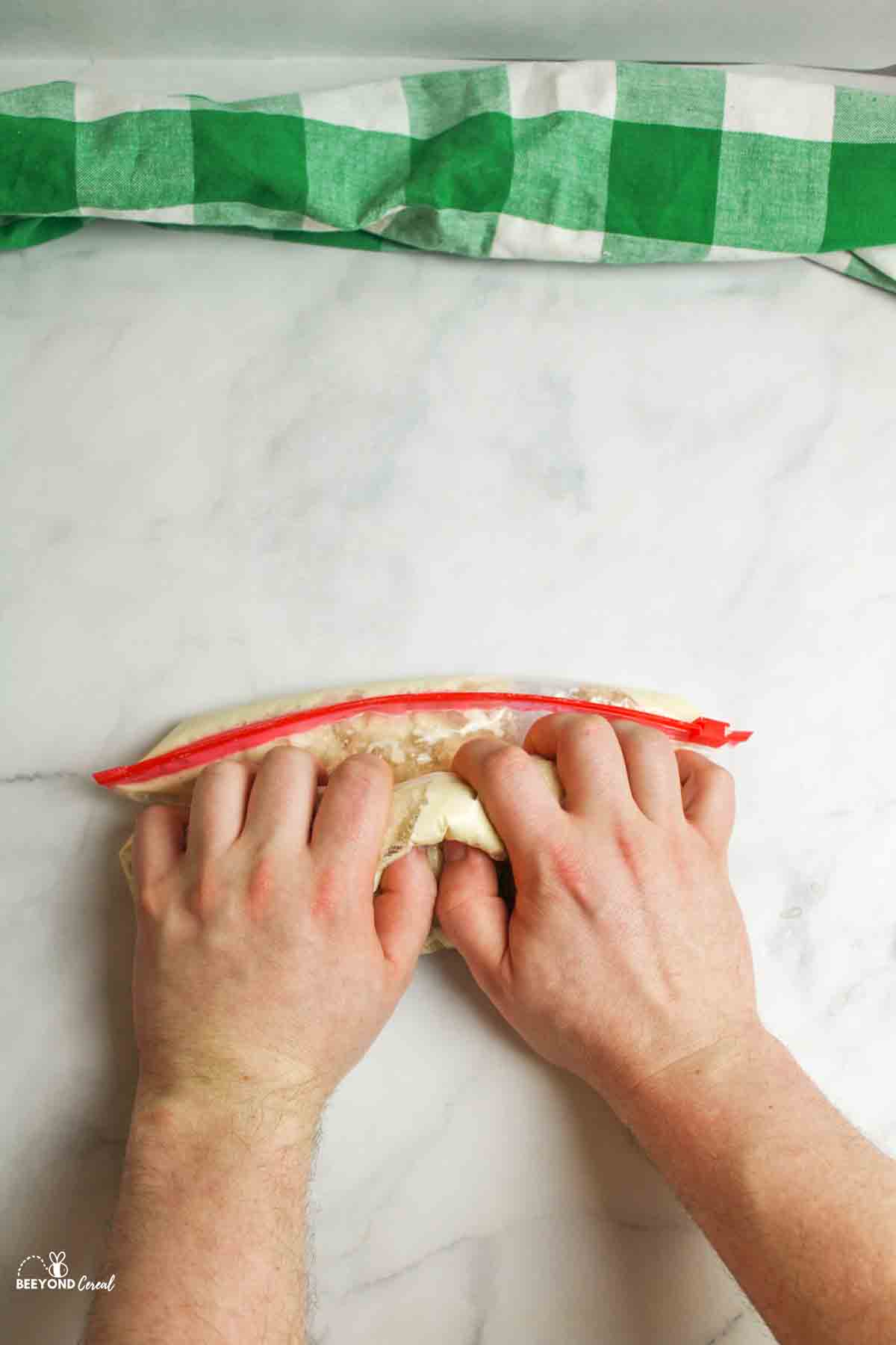 hands kneading the bag of pizza dough ingredients together.