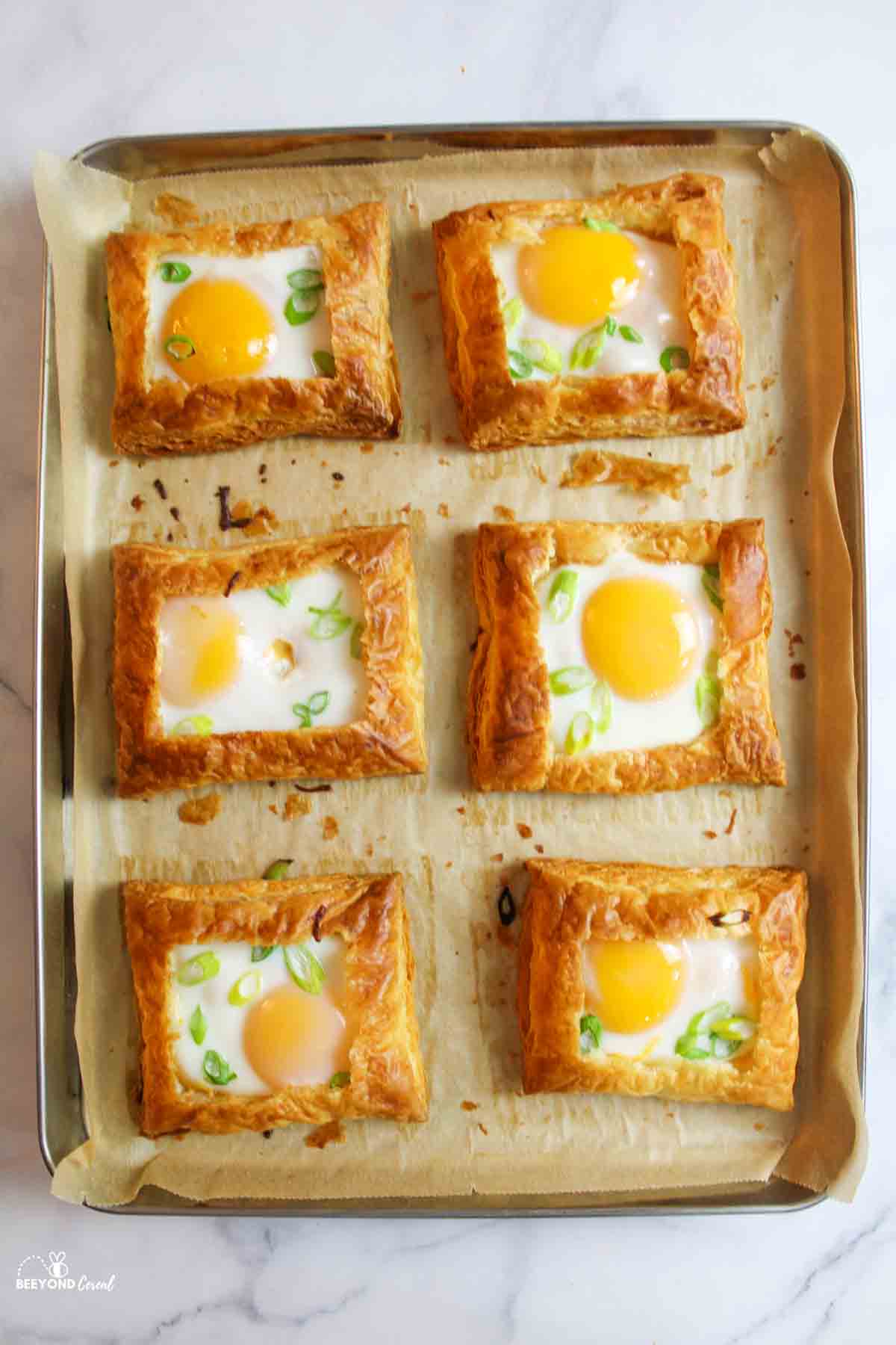 baked puff pastry egg tarts on a parchment paper lined baking sheet