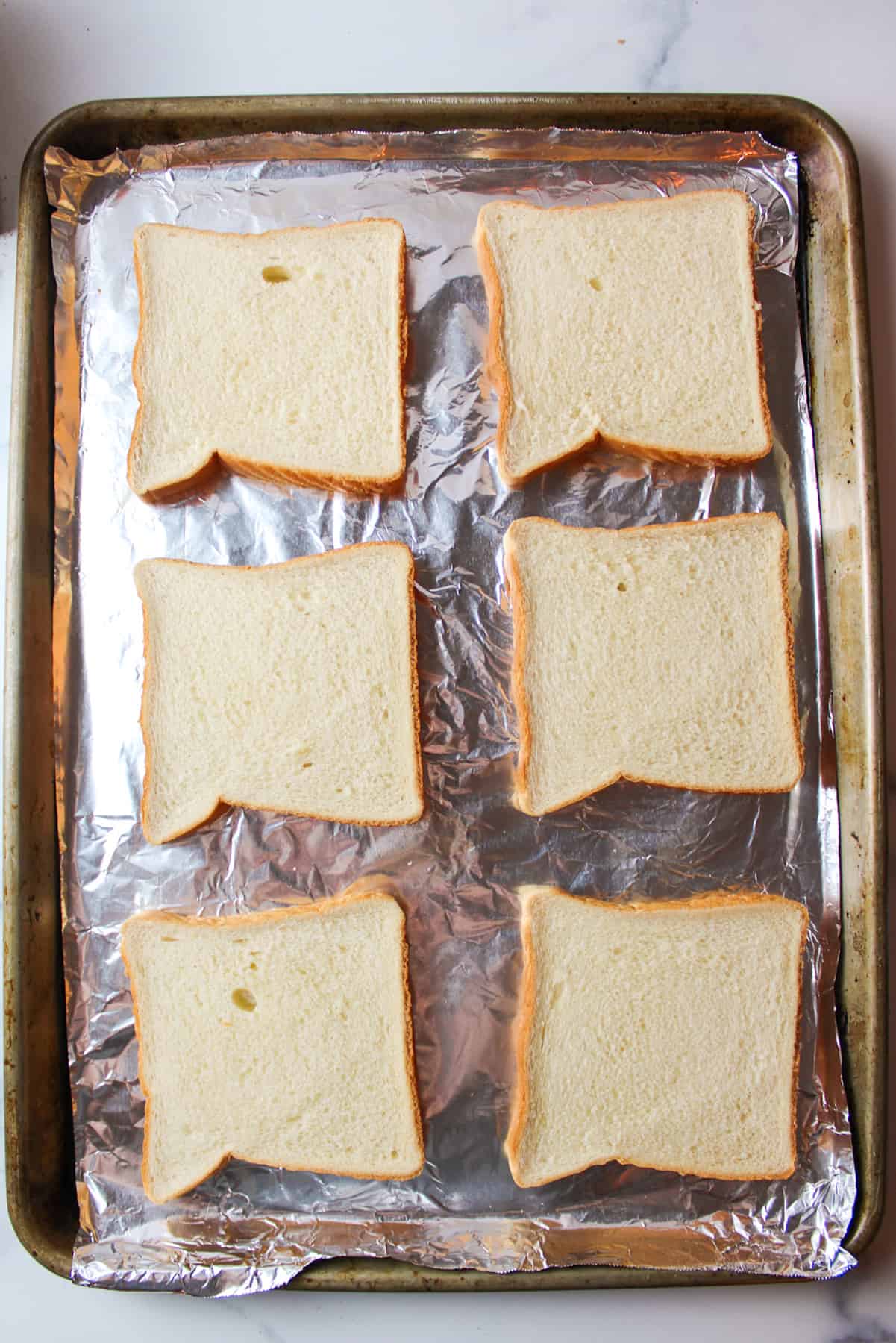 6 slices of sandwich bread on baking sheet.