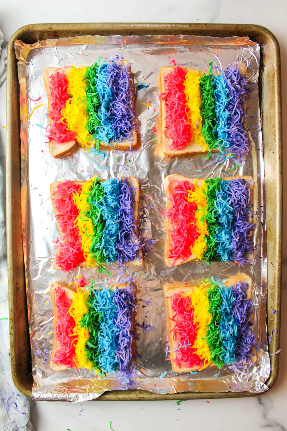 rainbow colored cheese on bread on baking sheet.