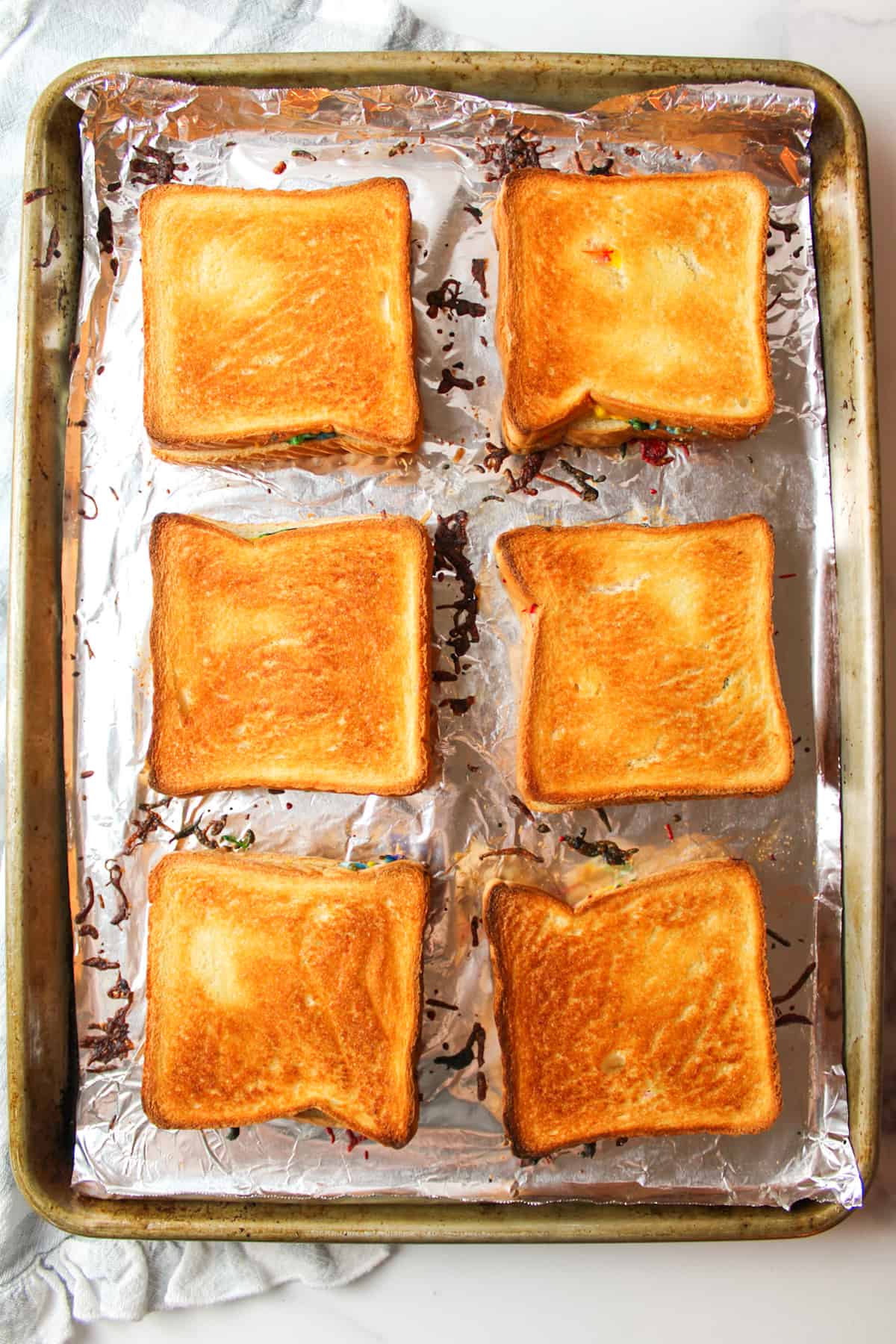 toasted rainbow grilled cheese sandwiches on a baking sheet