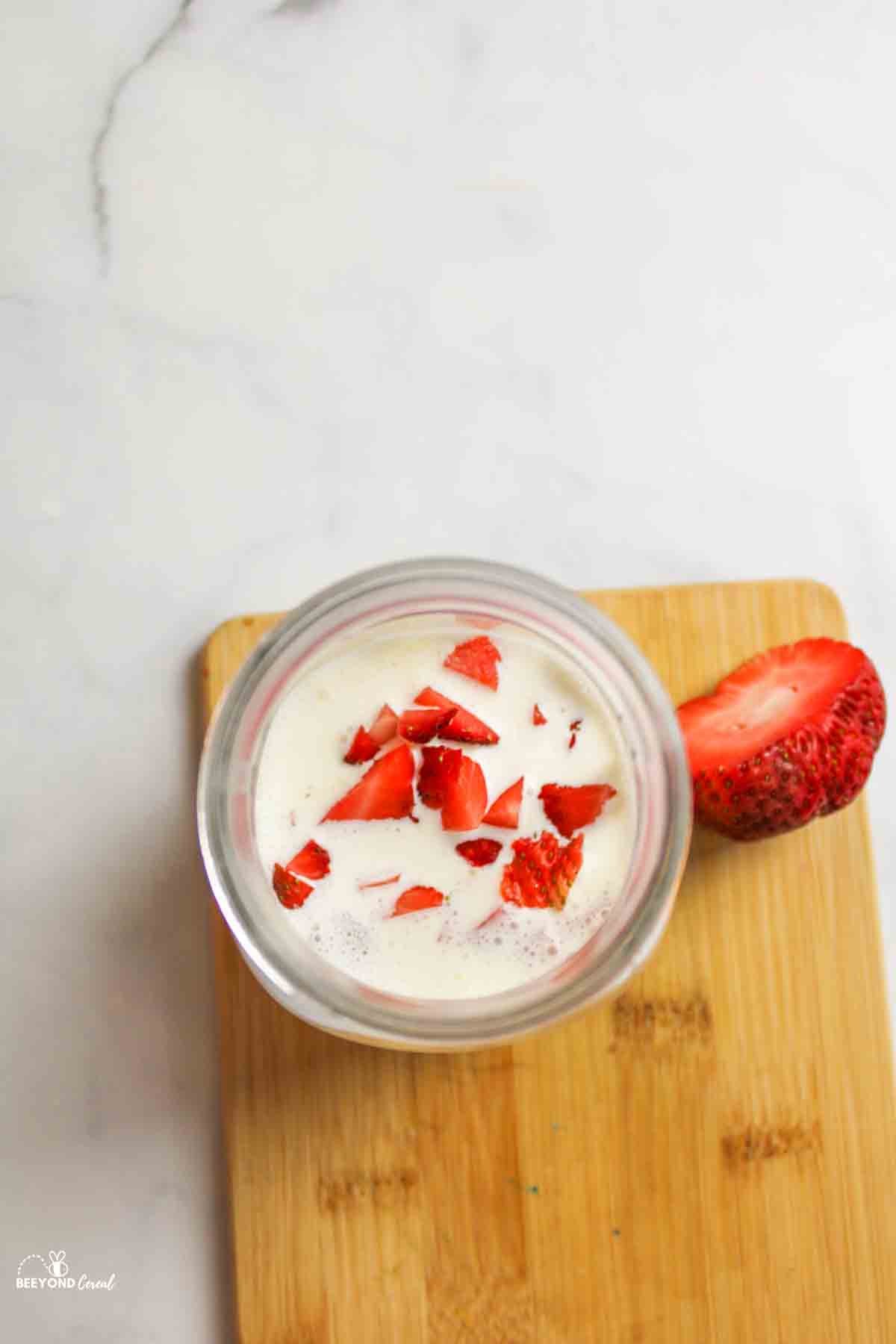 chopped strawberries added to mason jar of ice cream ingredients