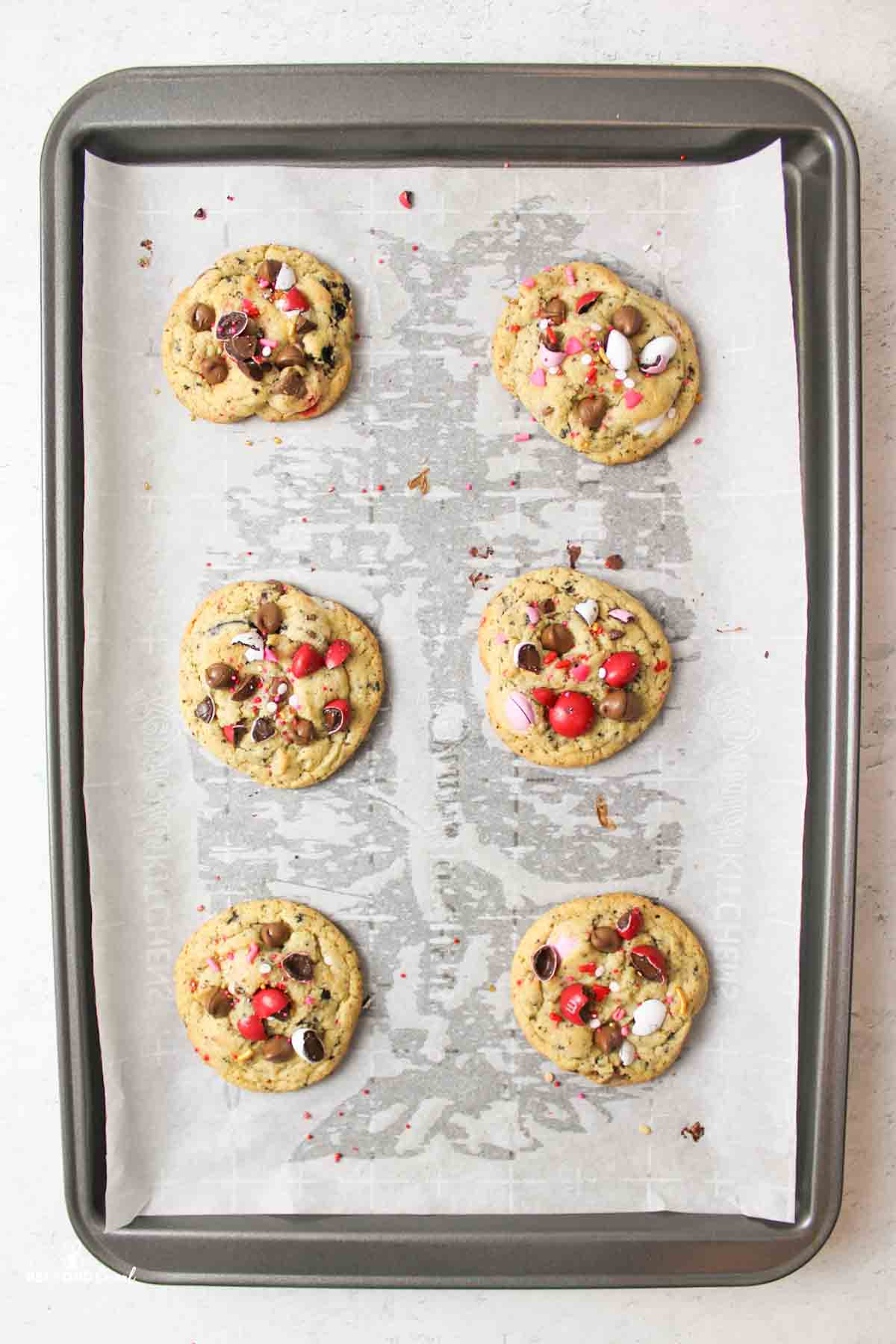 baked valentines cookies on a parchment paper lined baking sheet.