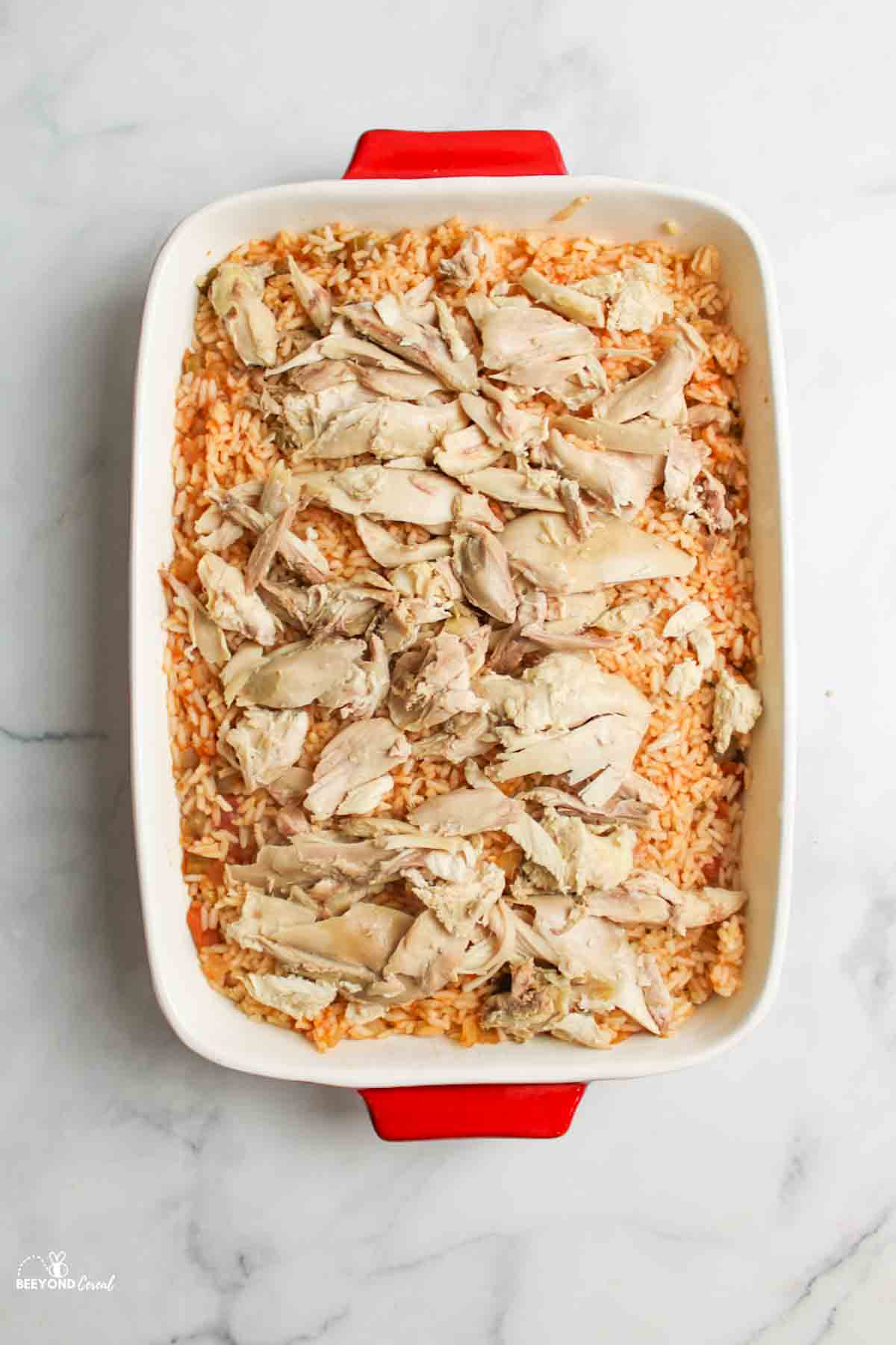 salsa rice in a baking dish topped with cooked chicken.
