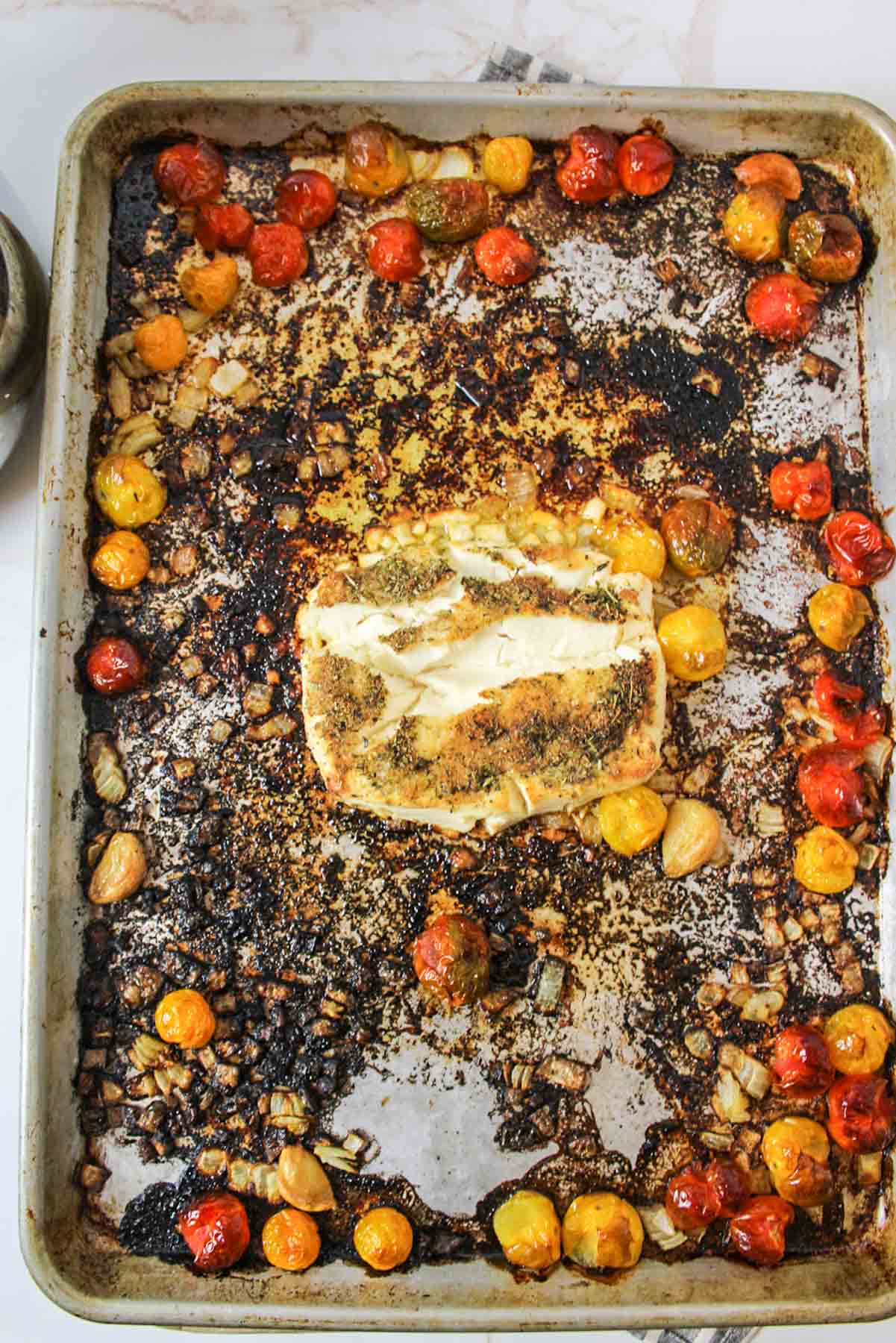 baked cream cheese and tomatoes on a darkened baking sheet.