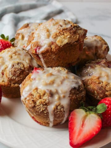 a plate full of strawberry muffins with fresh strawberries.