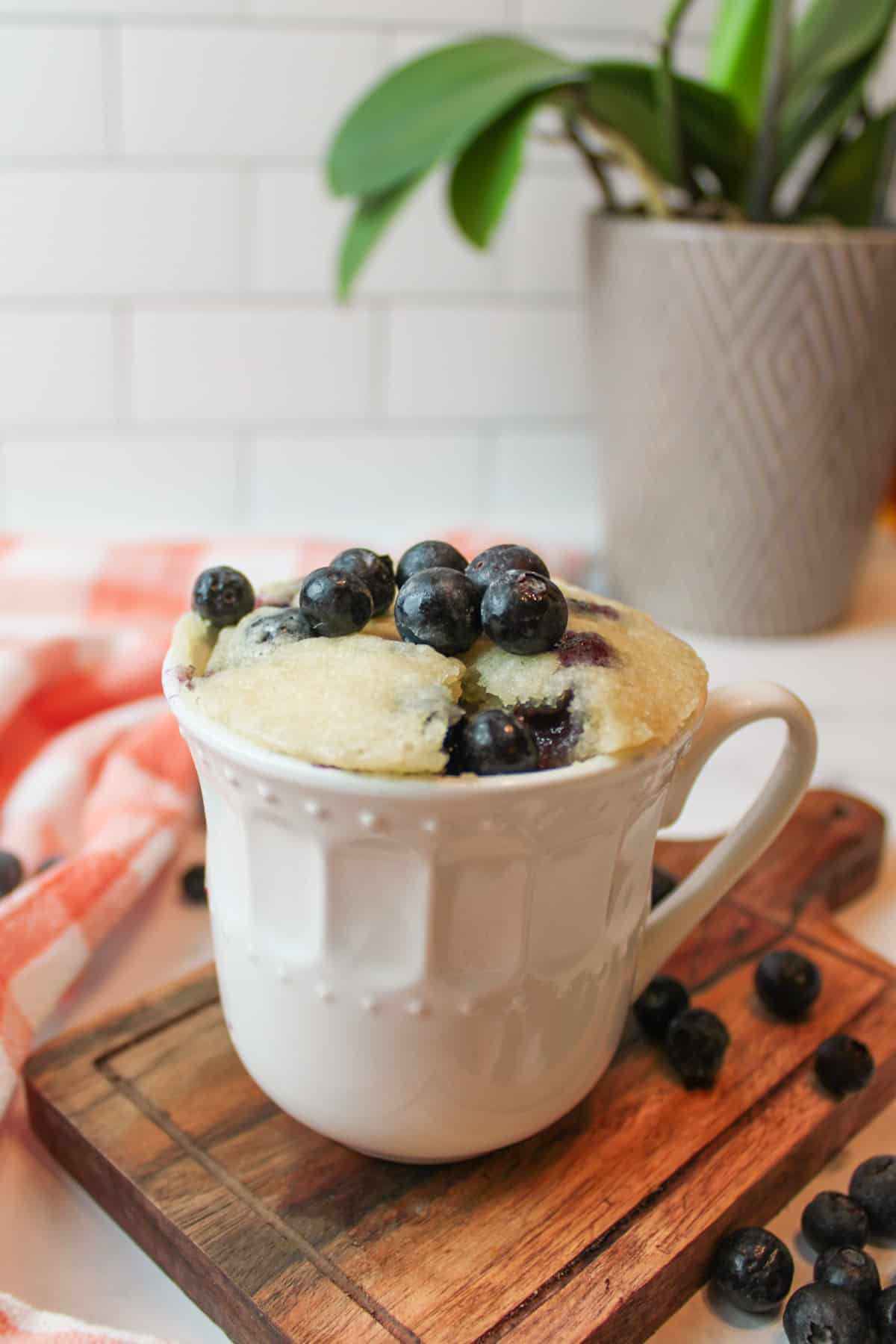 blueberries on a mug full of blueberry muffin