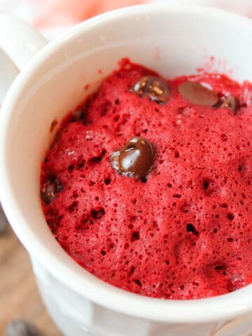 red velvet cake in a mug with chocolate chips.