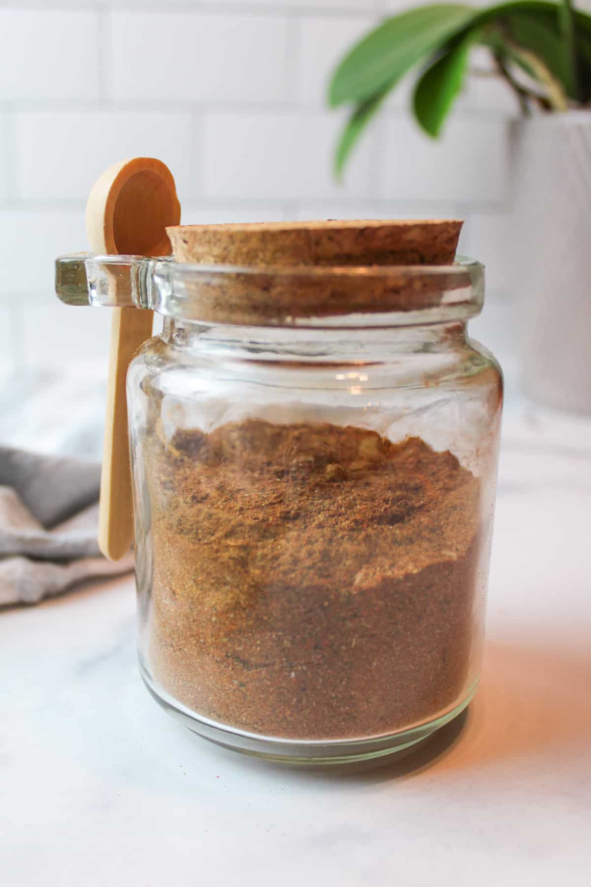 taco seasoning in a sealed jar with a wooden spoon