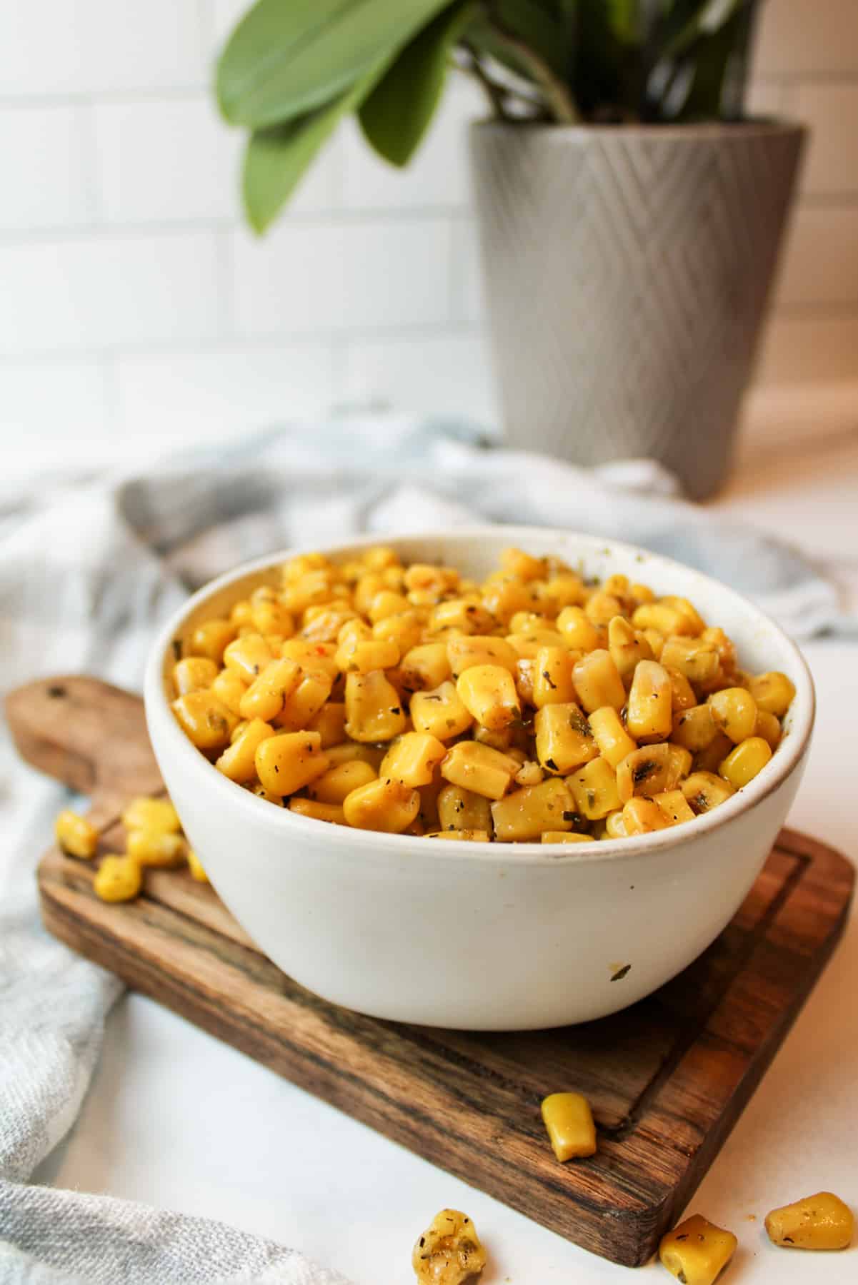 cooked canned corn in a bowl with some corn scattered around it.