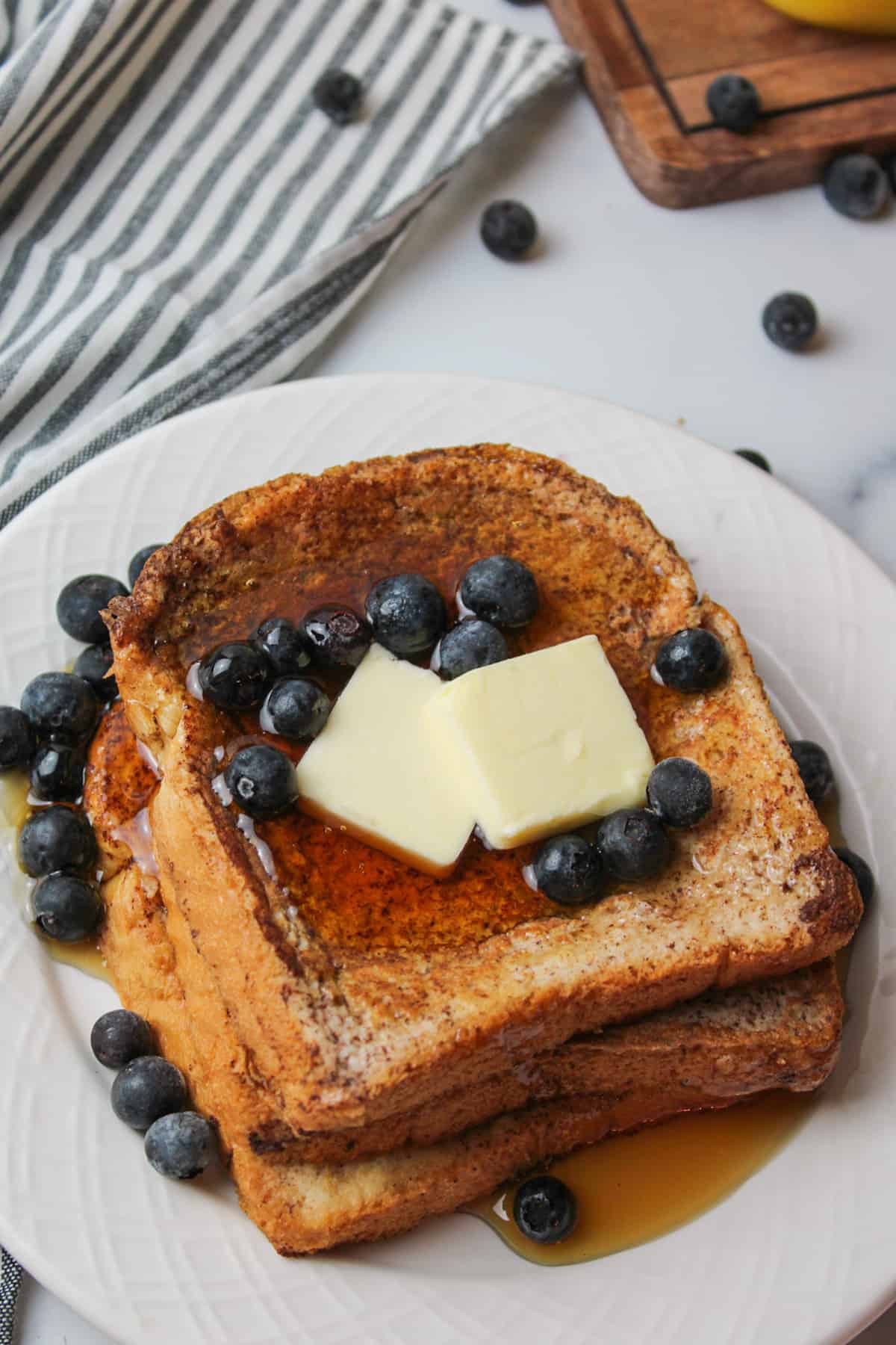 maple syrup butter and blueberry topped french toast slices on a plate.