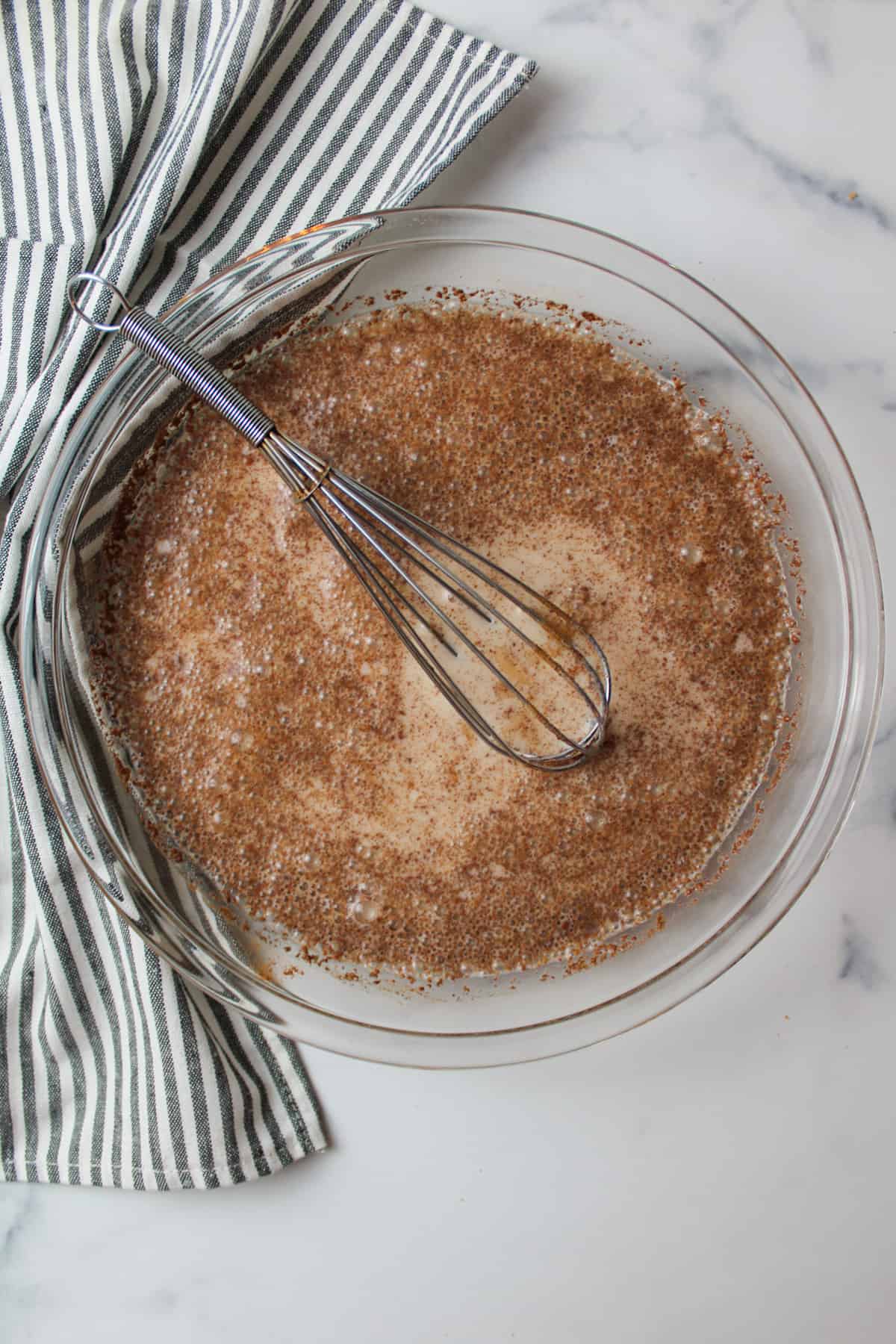 cinnamon egg mixture in a pie plate with a whisk.