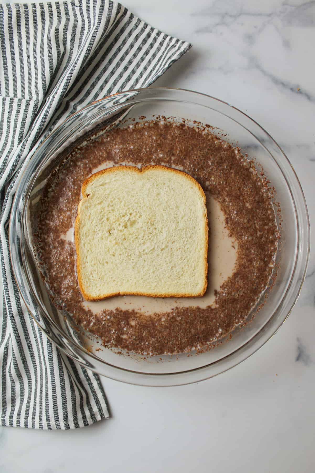 slice of bread in a pie plate of french toast egg mixture.