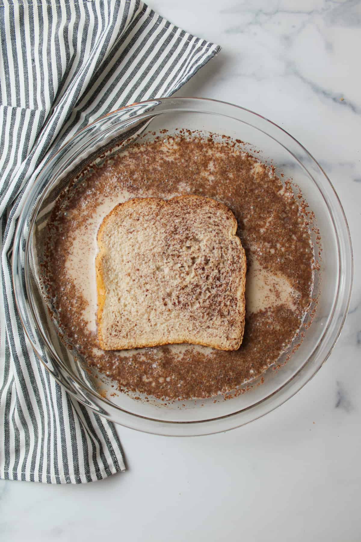 french toast mixture with a bread slice soaking in it.