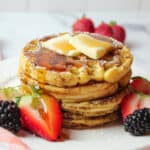 up close view of syrup and butter topped stacked waffles french toast and fresh berries