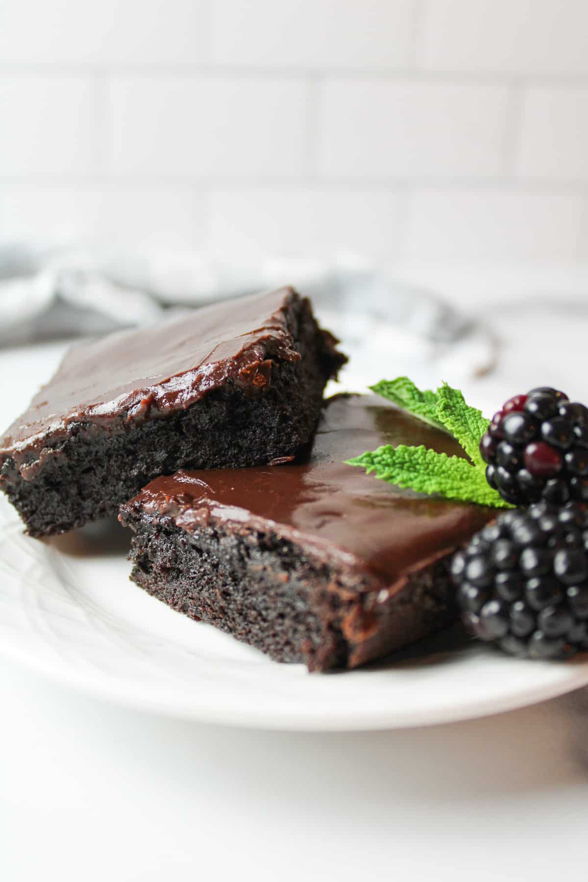 two slices of hershey brownies on a plant with mint leaves and blackberries