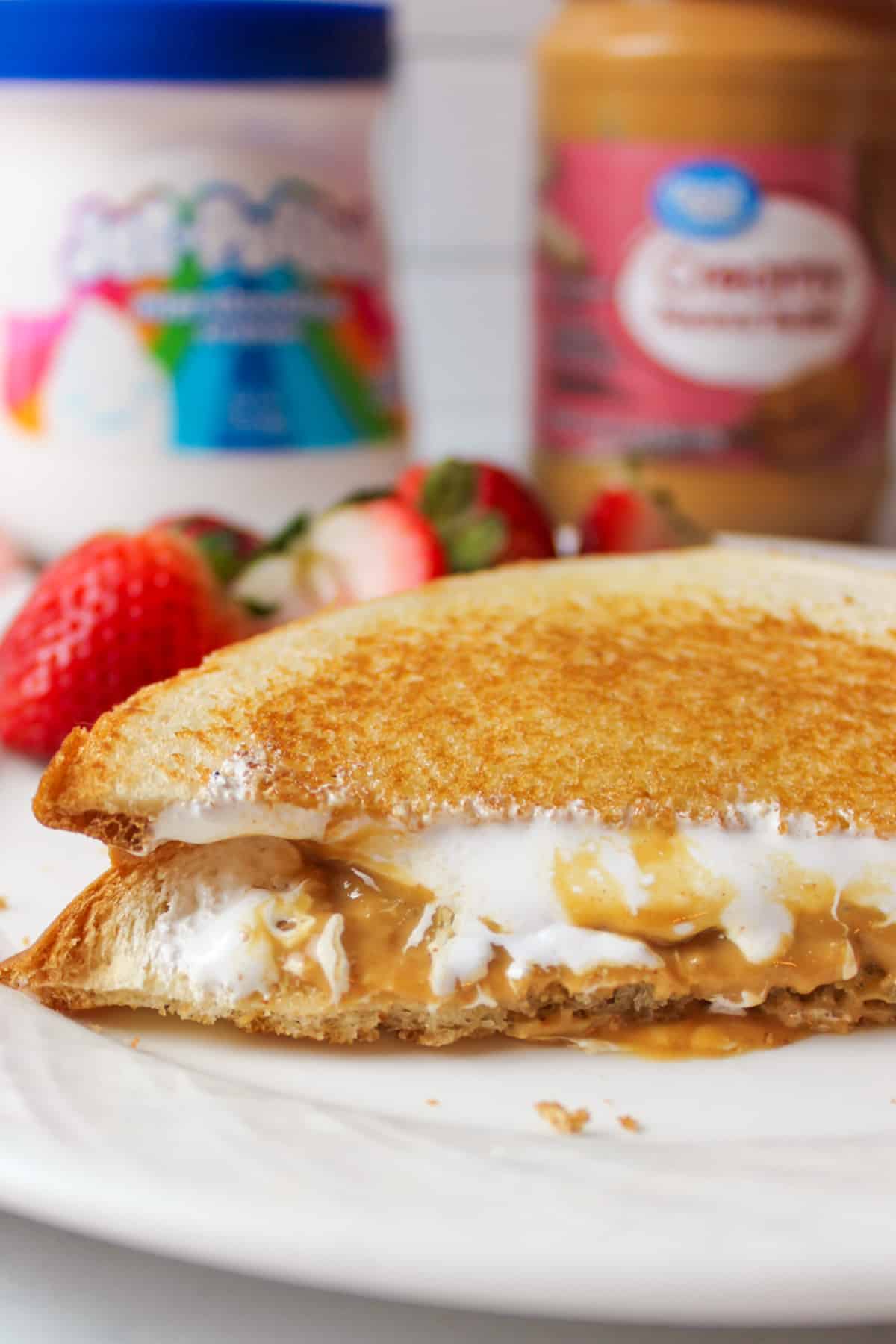 an upclose view of sliced grilled fluffternutter sandwich on a plate with fresh strawberries