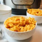 a close up of a bowl of kraft mac and cheese with more in the background in front of an instant pot