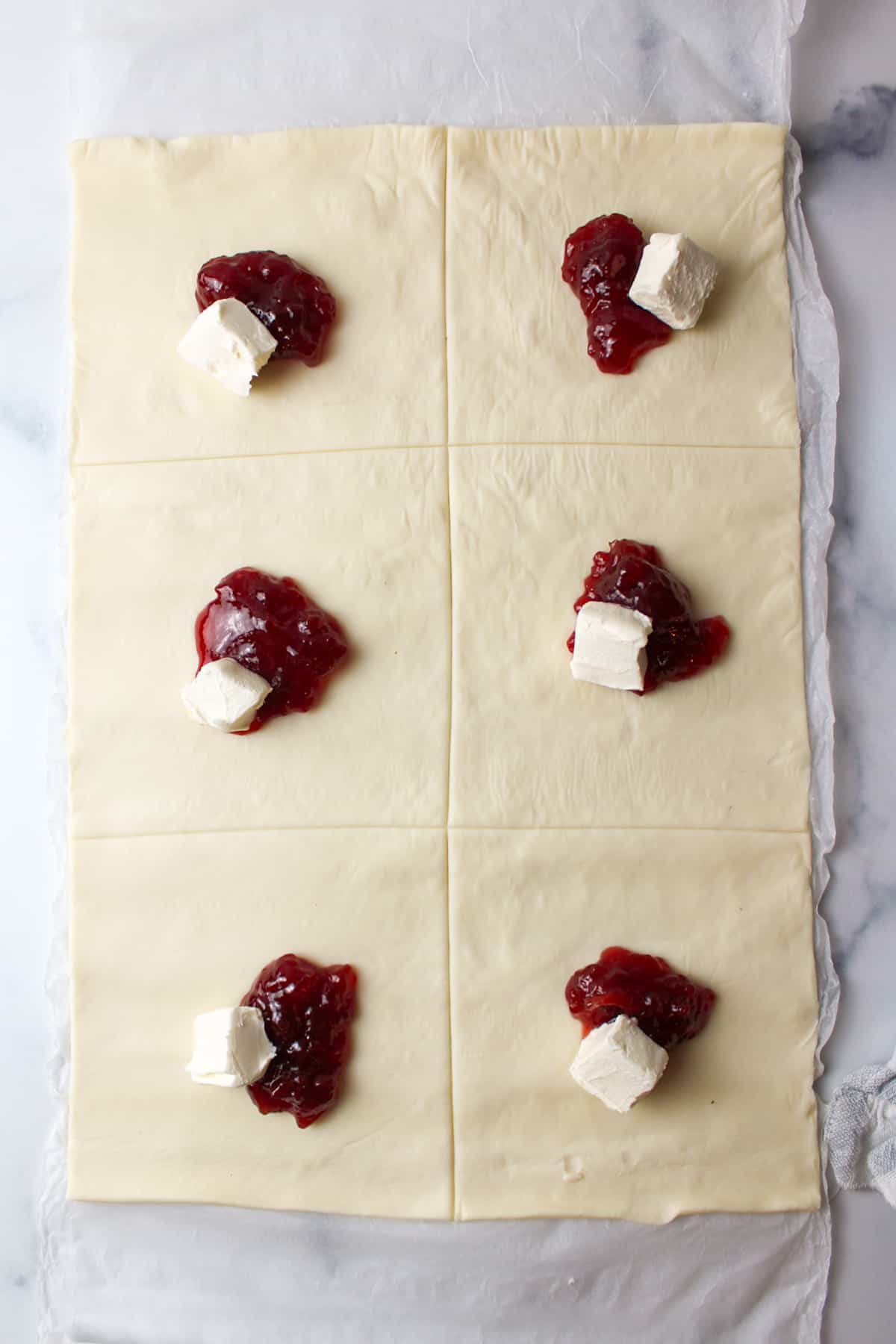 puff pastry squares topped with cream cheese and strawberry jam.