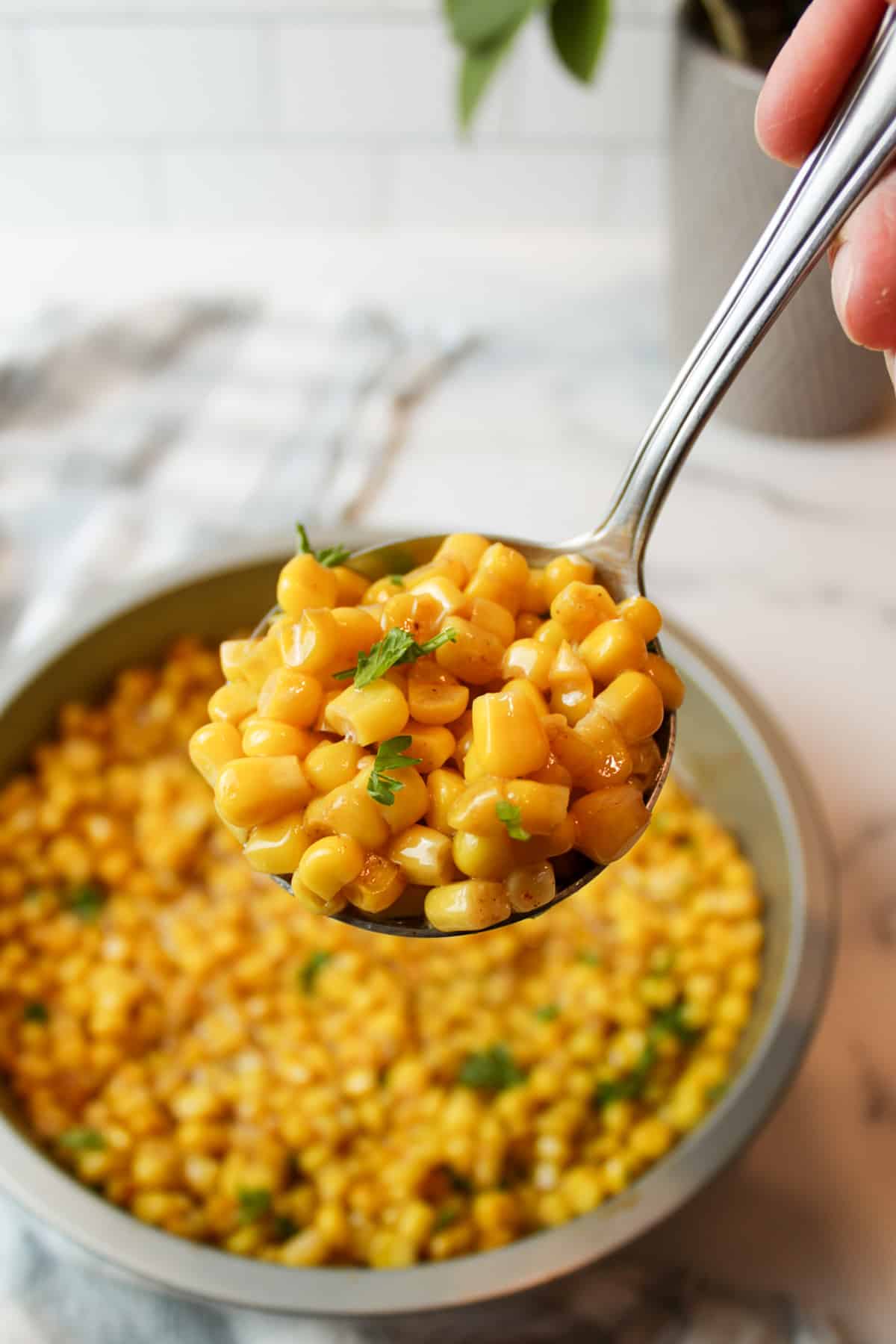 a spoon of cooked corn kernels and fresh parsley.