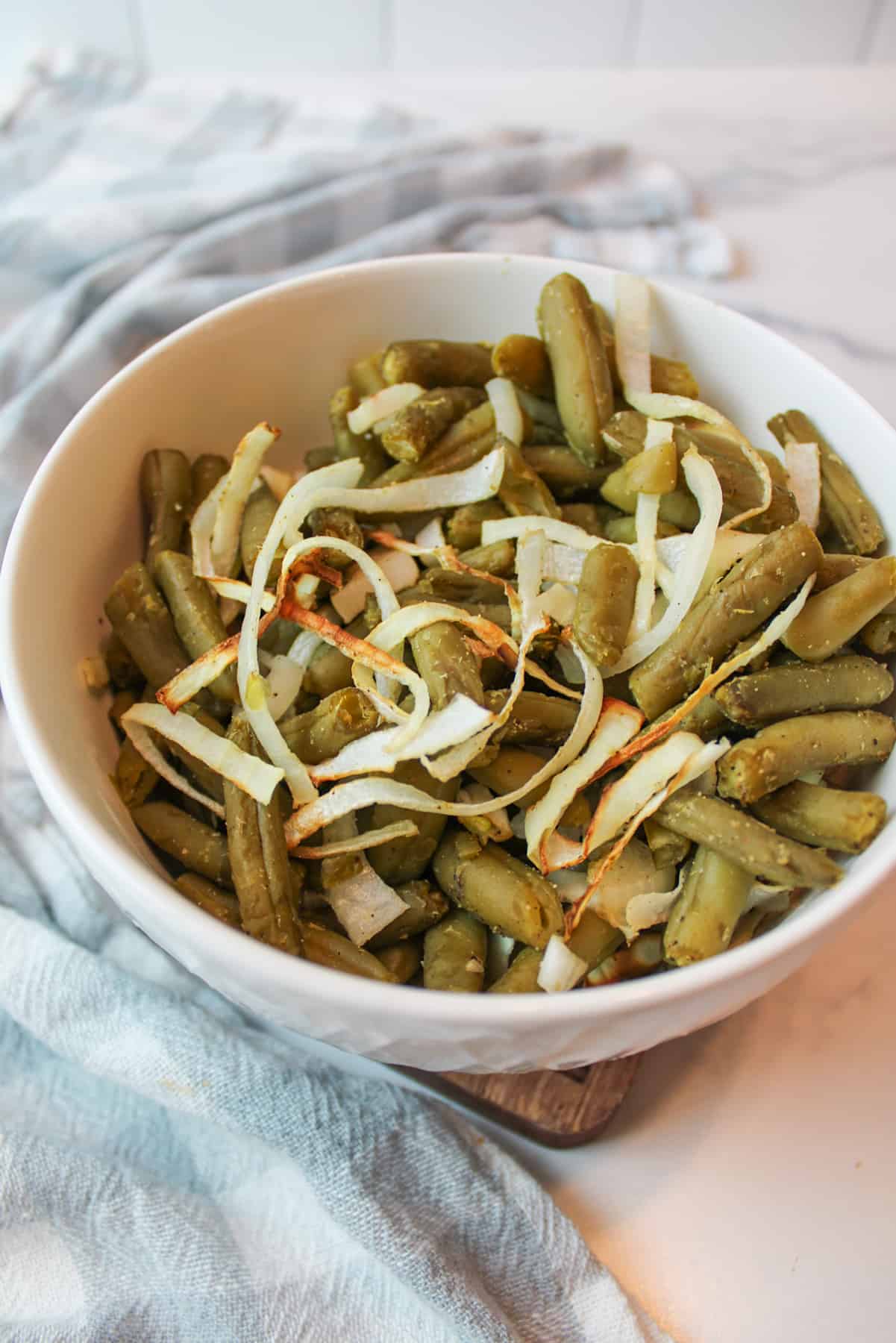 a bowl full of cooked green beans and onion.