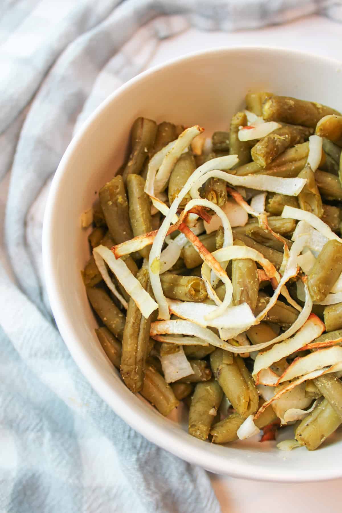 a bowl filled with air fryer green beans and onions.