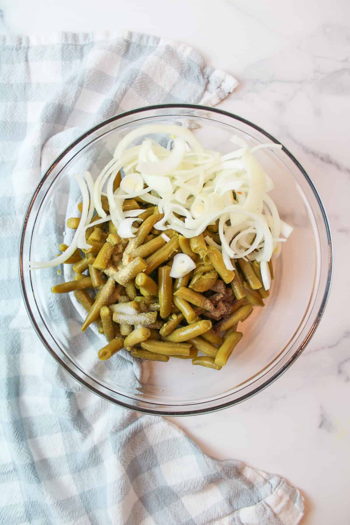 a bowl full of drained canned green beans, onion, and seasonings