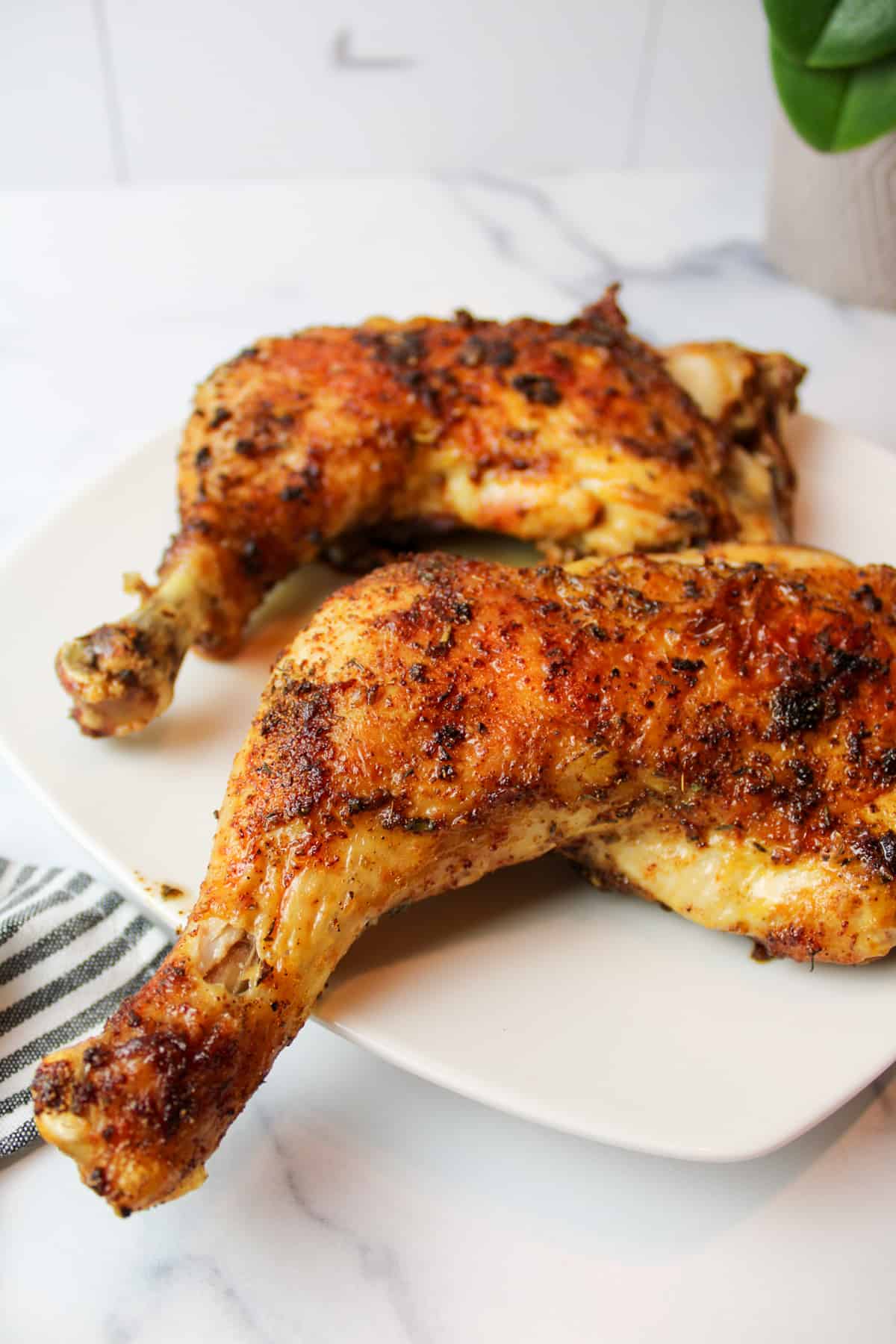 Two air-fried chicken quarters on plate, one leg extending over plate edge.