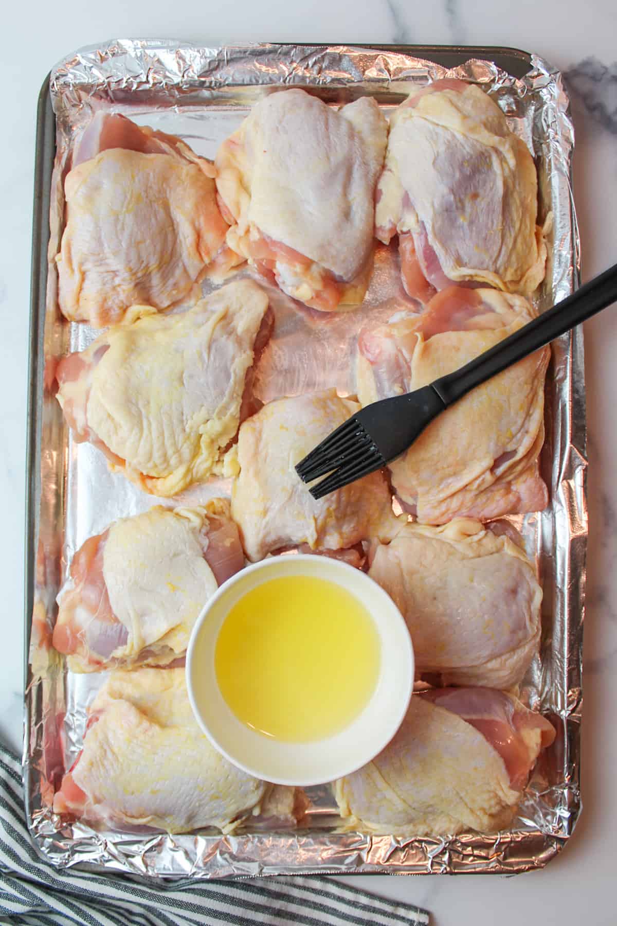 brushing olive oil over the top of the chicken thigh skin on a foil lined baking sheet