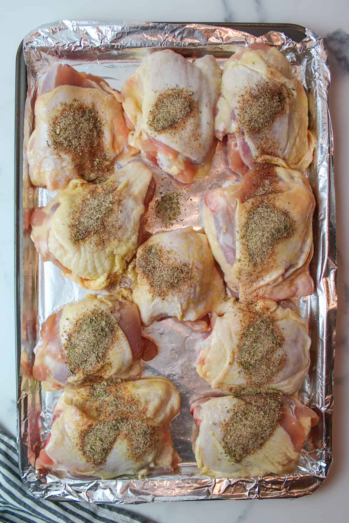 sprinkled mixed seasonings over chicken thighs on a foil lined baking sheet