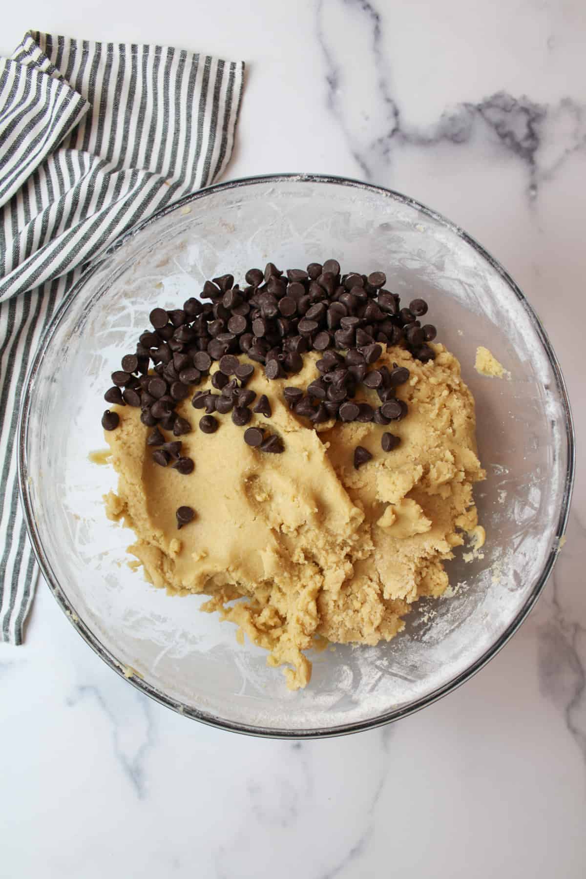 chocolate chips added to mixing bowl with cookie dough inside.