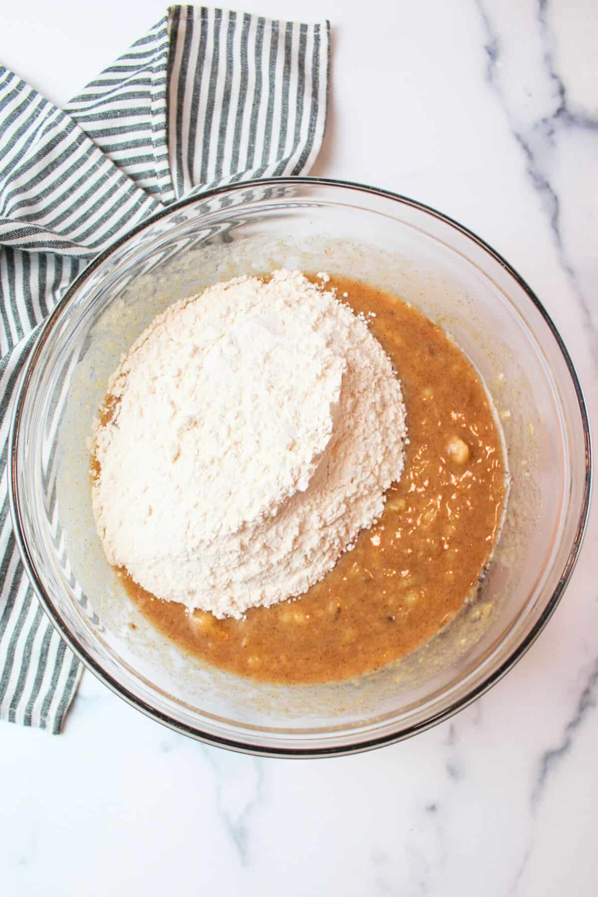 flour added to sugar and banana mixture in a mixing bowl.