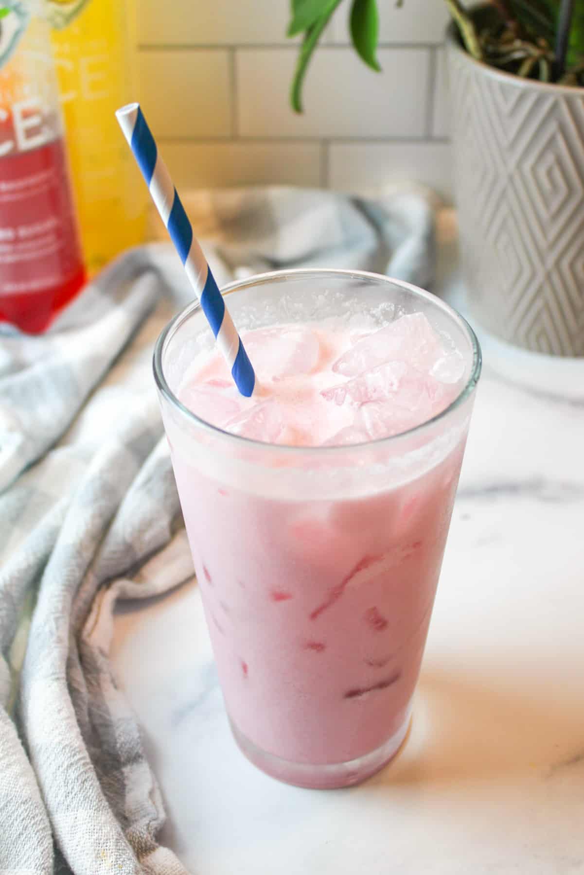 an icey cold drink in a glass with a blue and white striped straw.