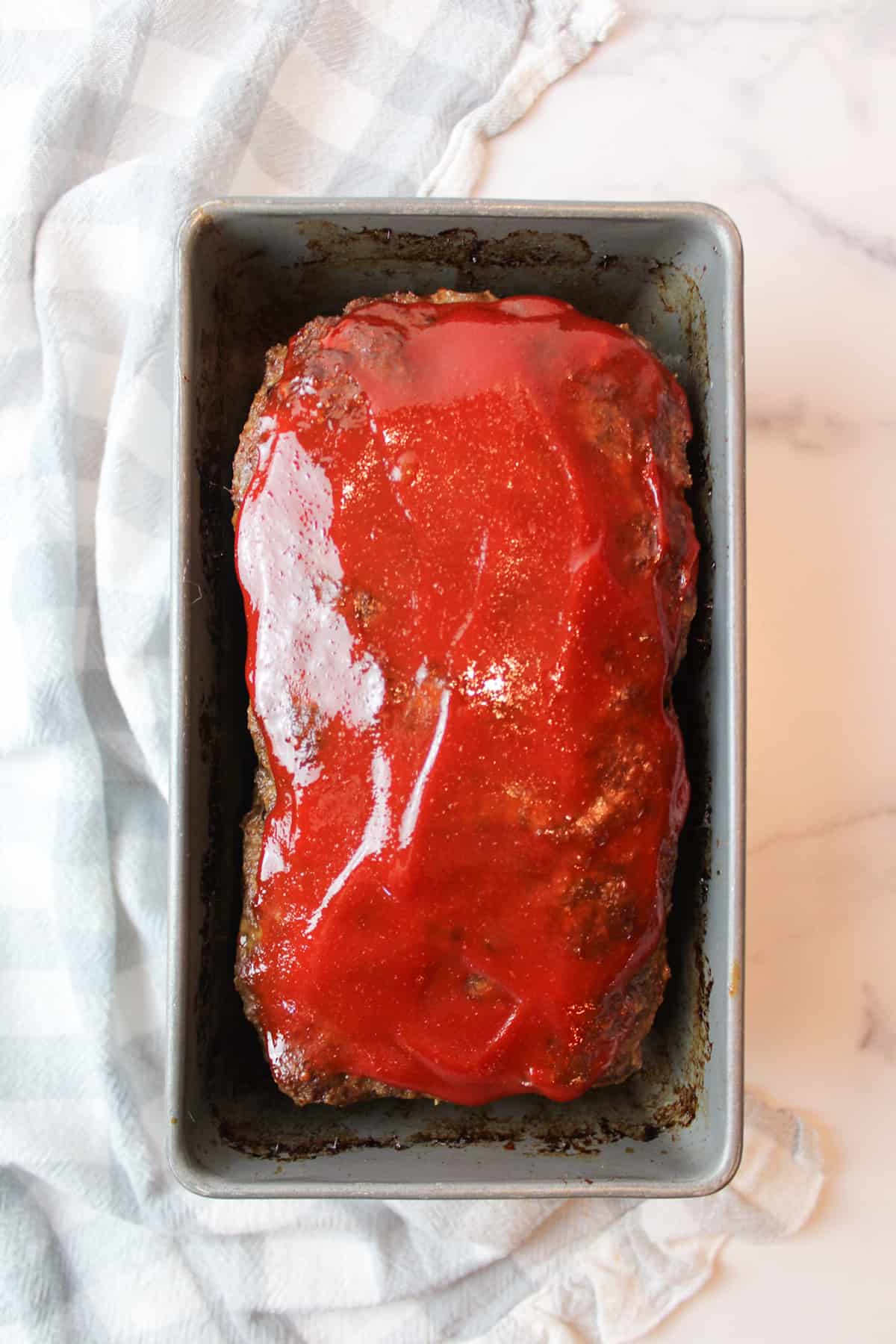 aerial view of cooked meatloaf and ketchup topping in a bread loaf pan