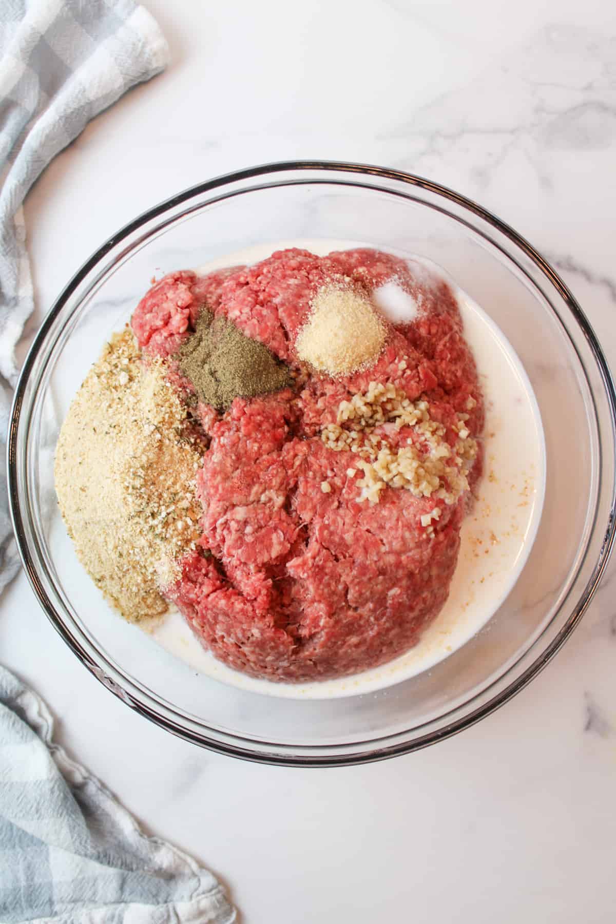 all of the meatloaf ingredients except ketchup added to a mixing bowl.